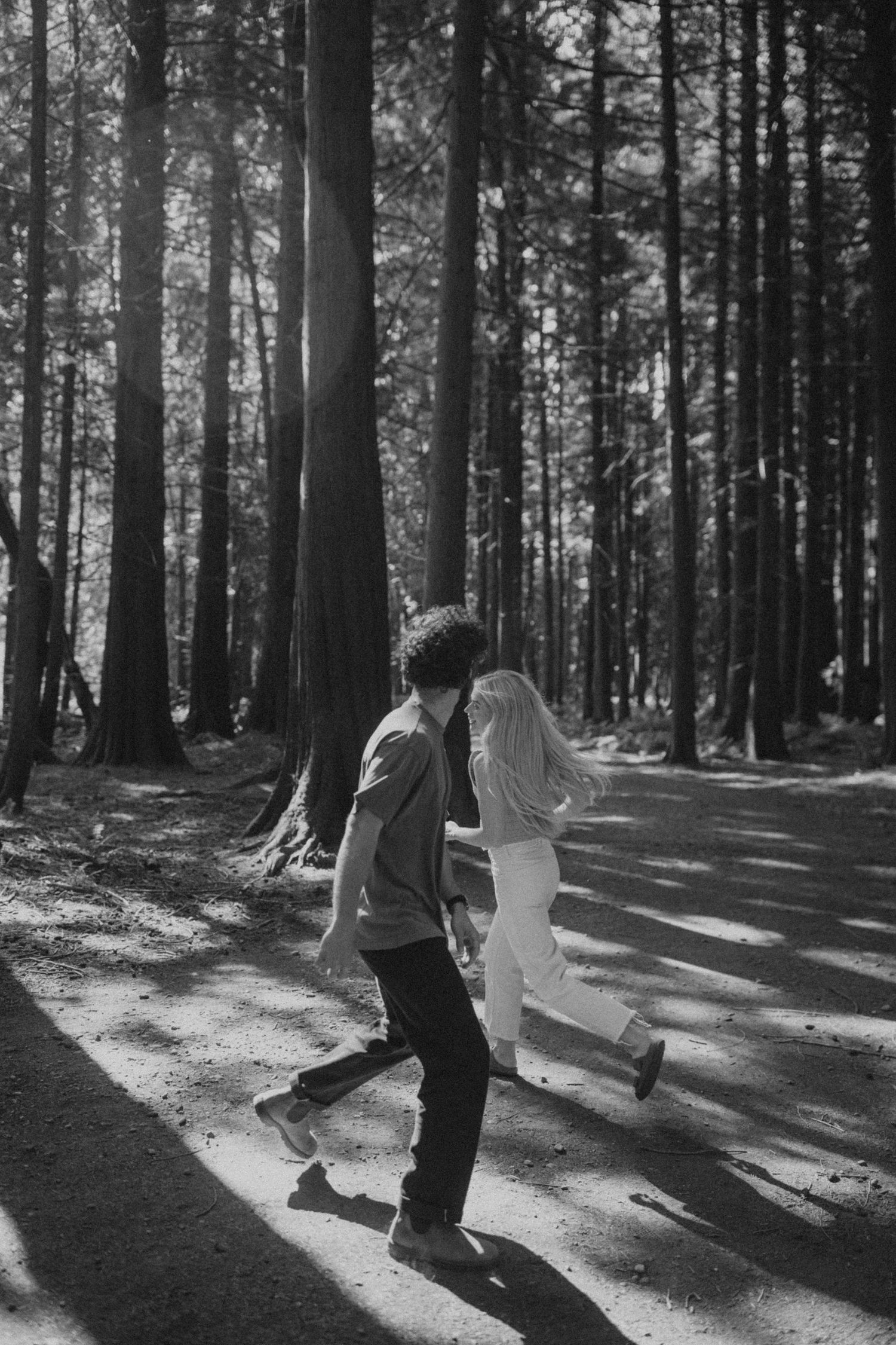 A couple dances together in dramatic black and white lighting among forest shadows.
