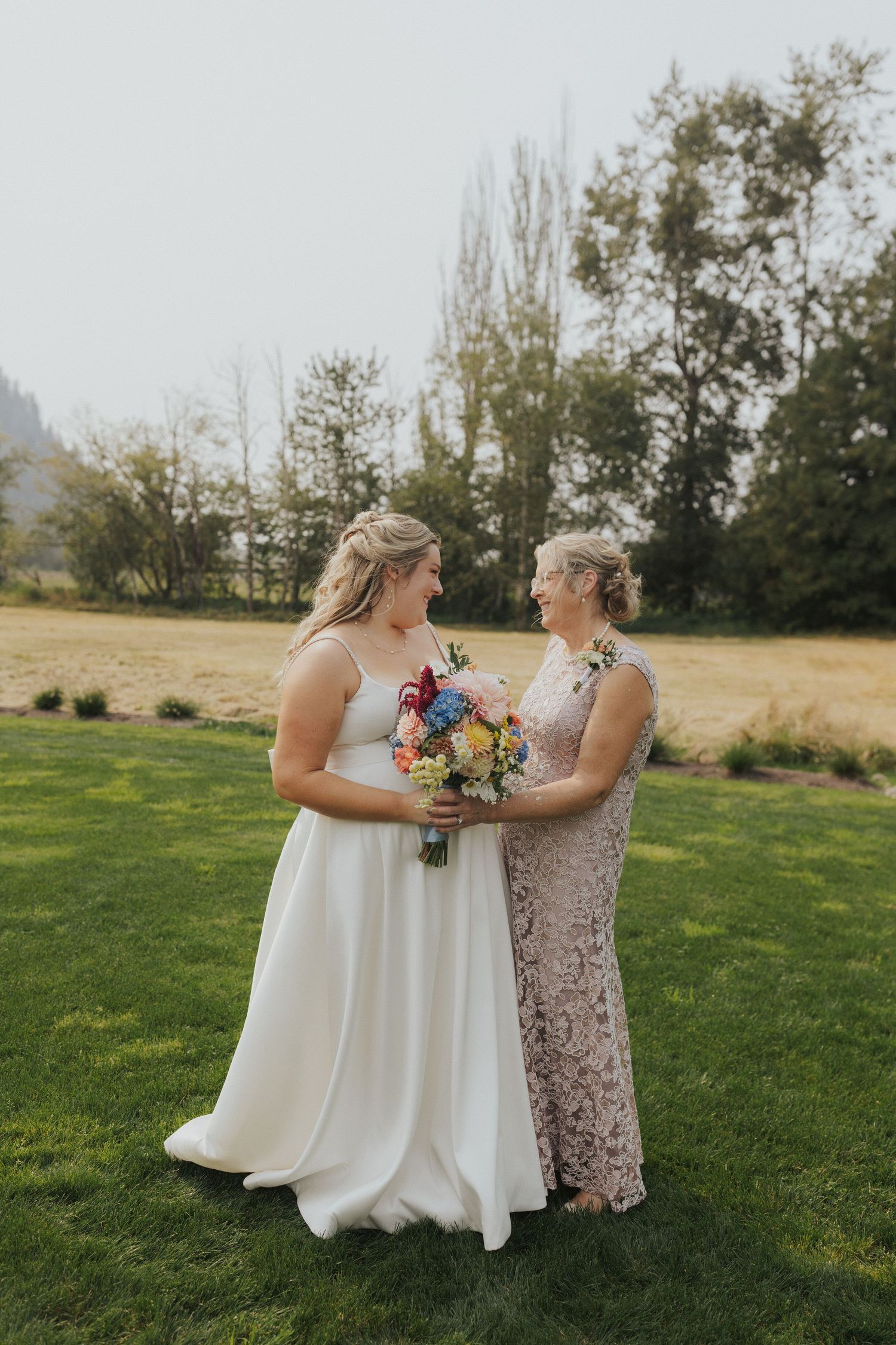 Wedding celebration on a green lawn with bright floral bouquets and white dresses.