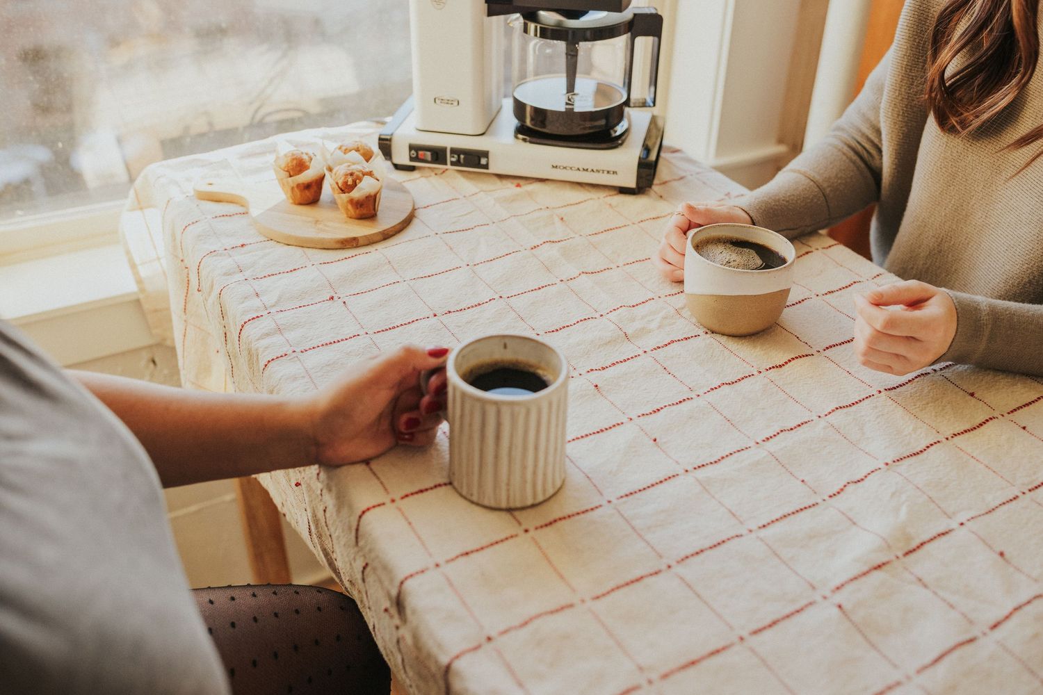 Checkered tablecloth on wooden surface with coffee and pastries.