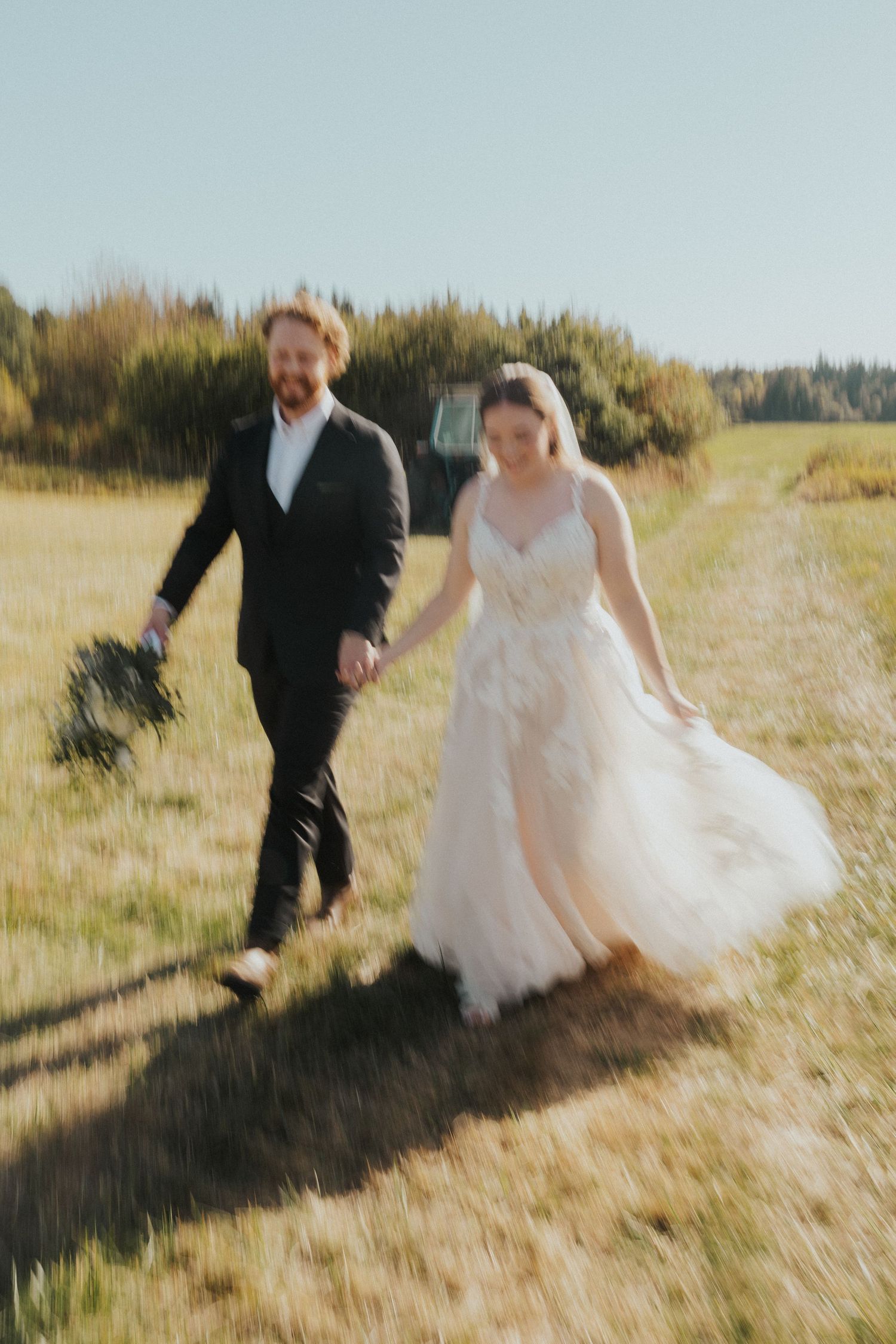 Candid wedding shots of a couple walking and laughing together in a sunlit field.