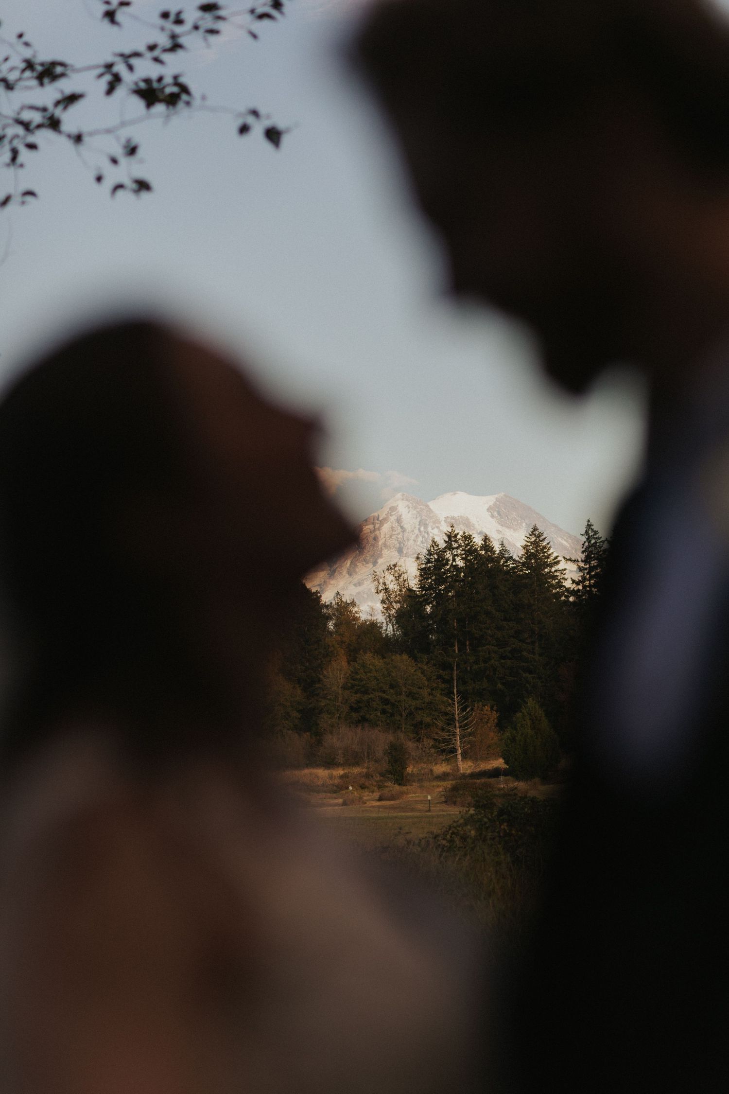 Mountain peak visible through silhouetted couple during sunset wedding photoshoot.