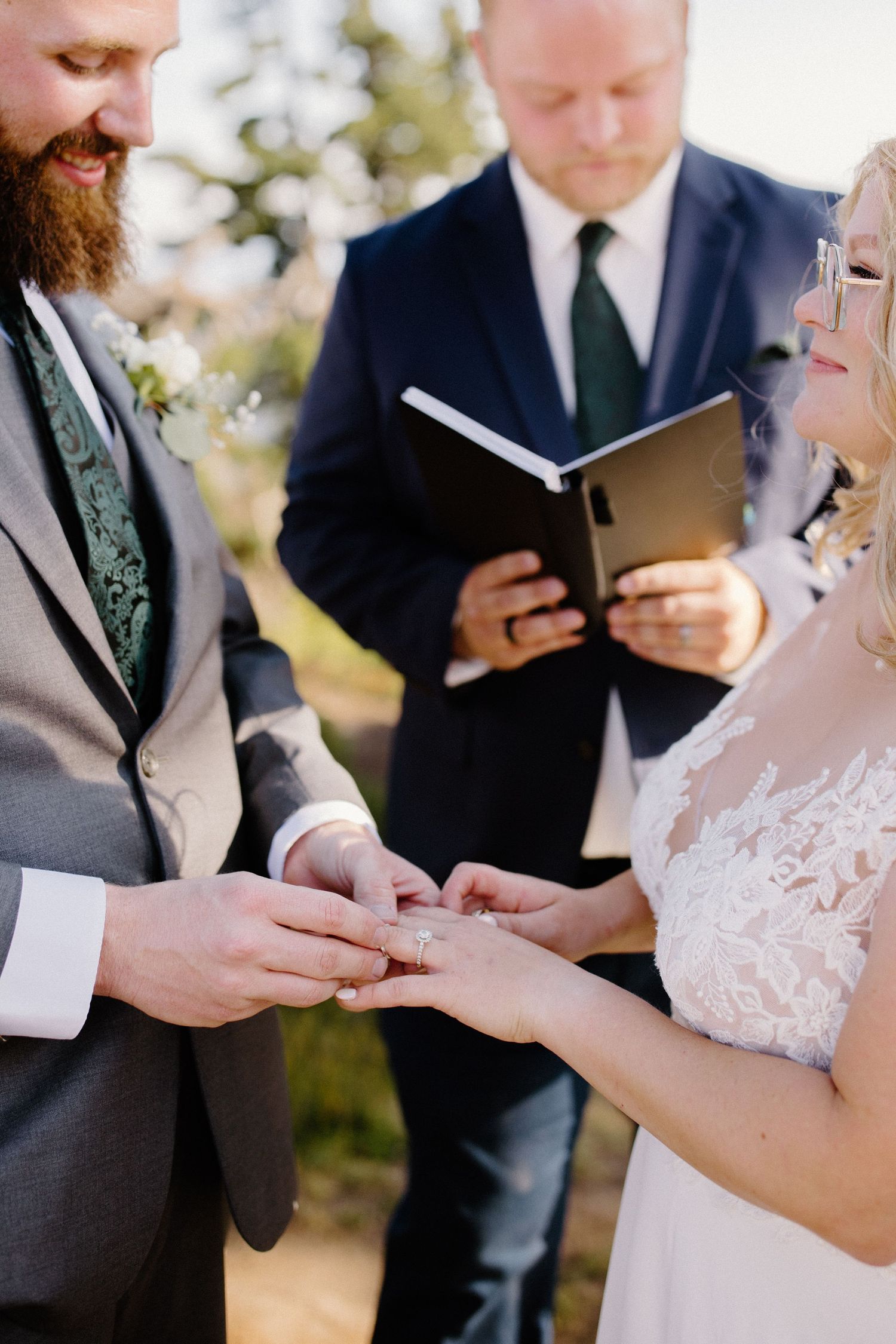 Close-up of hands exchanging rings during a mountain wedding ceremony.