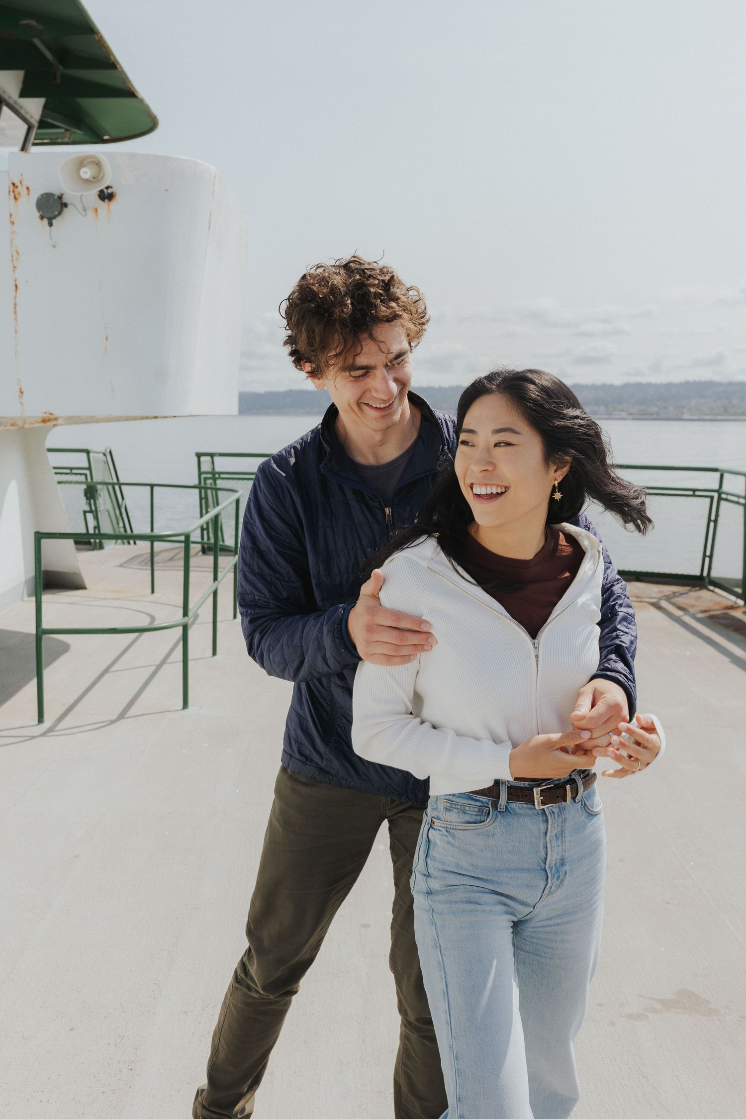 A joyful couple shares a candid moment while laughing together on a ferry deck.