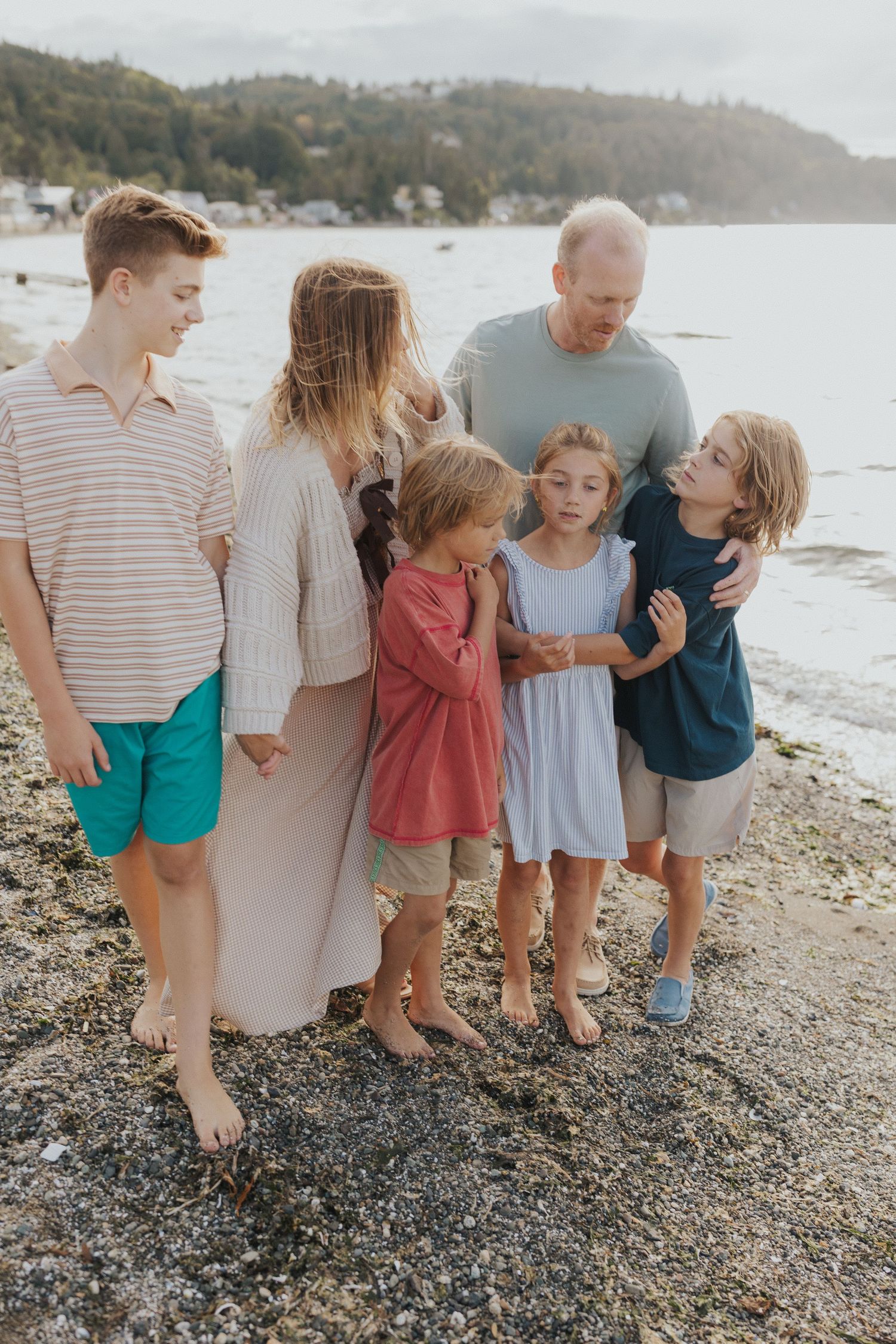 Family members lined up together on a rocky beach with mountains visible in the distance.
