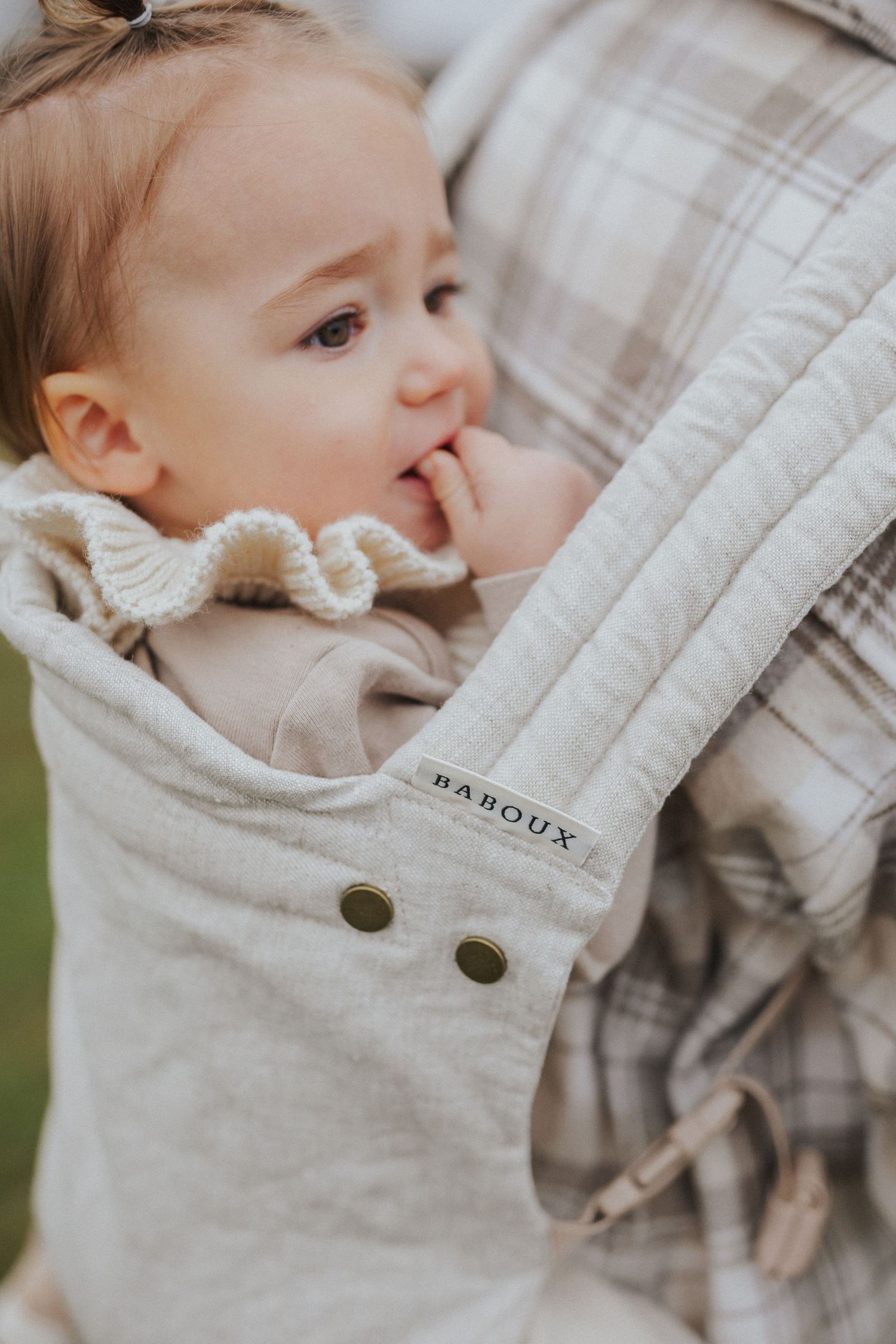 Close-up of baby wearing light colored clothing with button details.