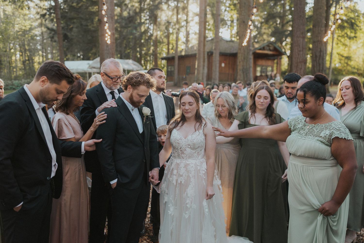 Wedding guests gather in a wooded setting during an intimate forest ceremony.