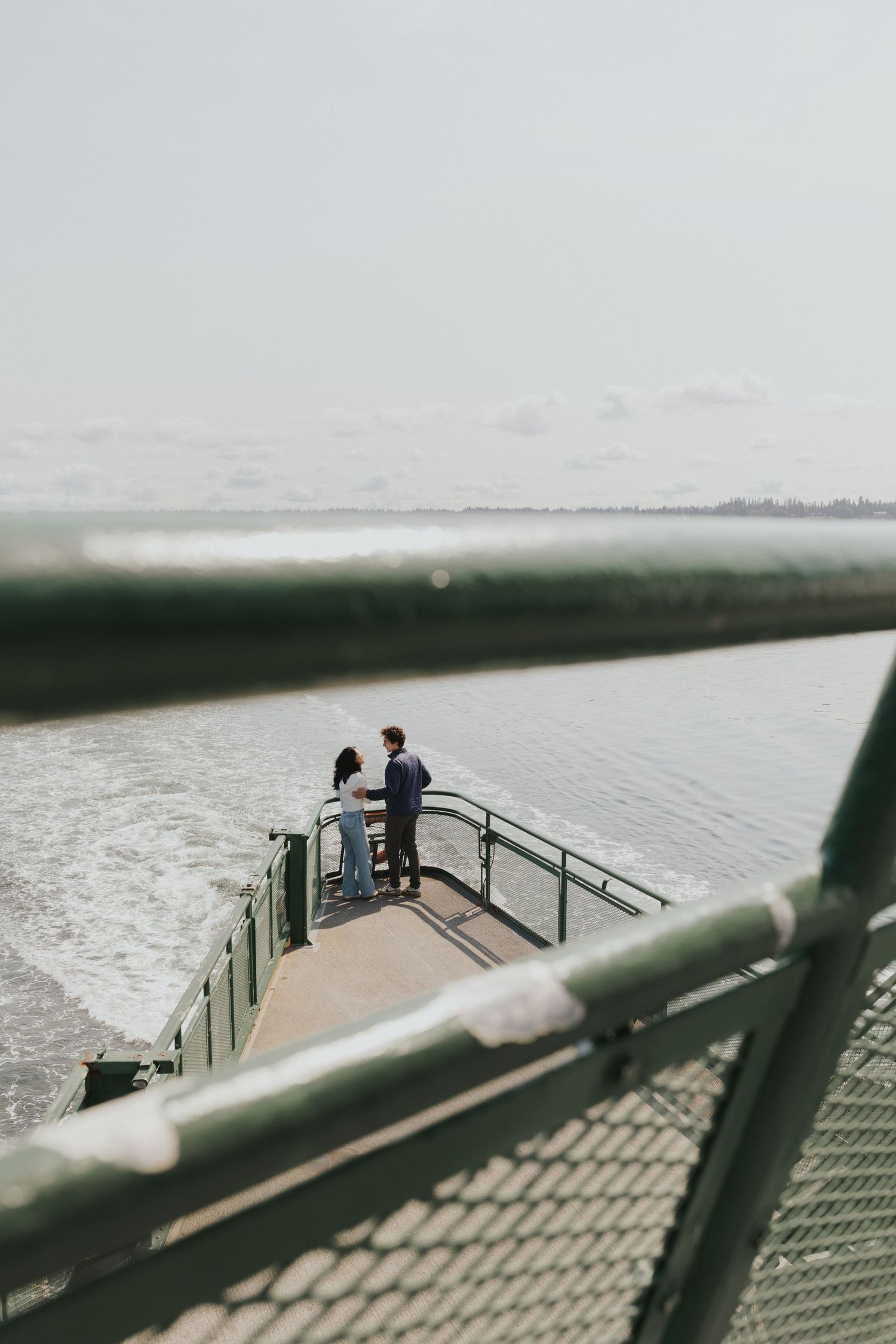 High angle view of a couple standing on a ferry deck observation platform.