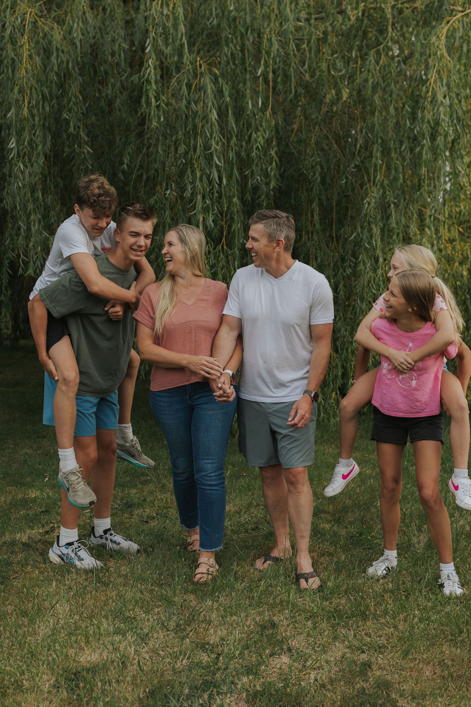 Casual family gathering with playful poses under willow tree branches.