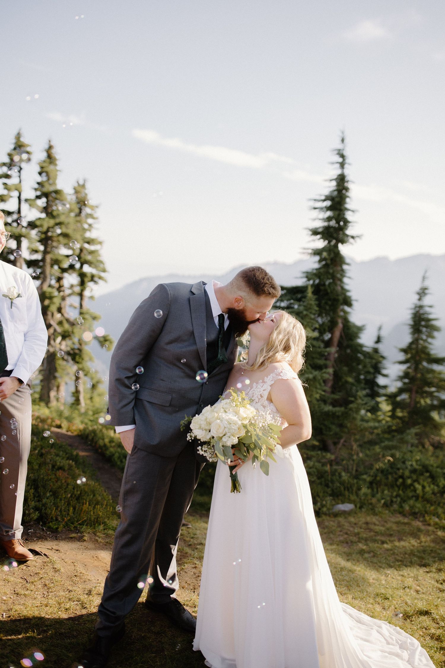 Newlyweds celebrate their mountain wedding with a romantic moment among pine trees.