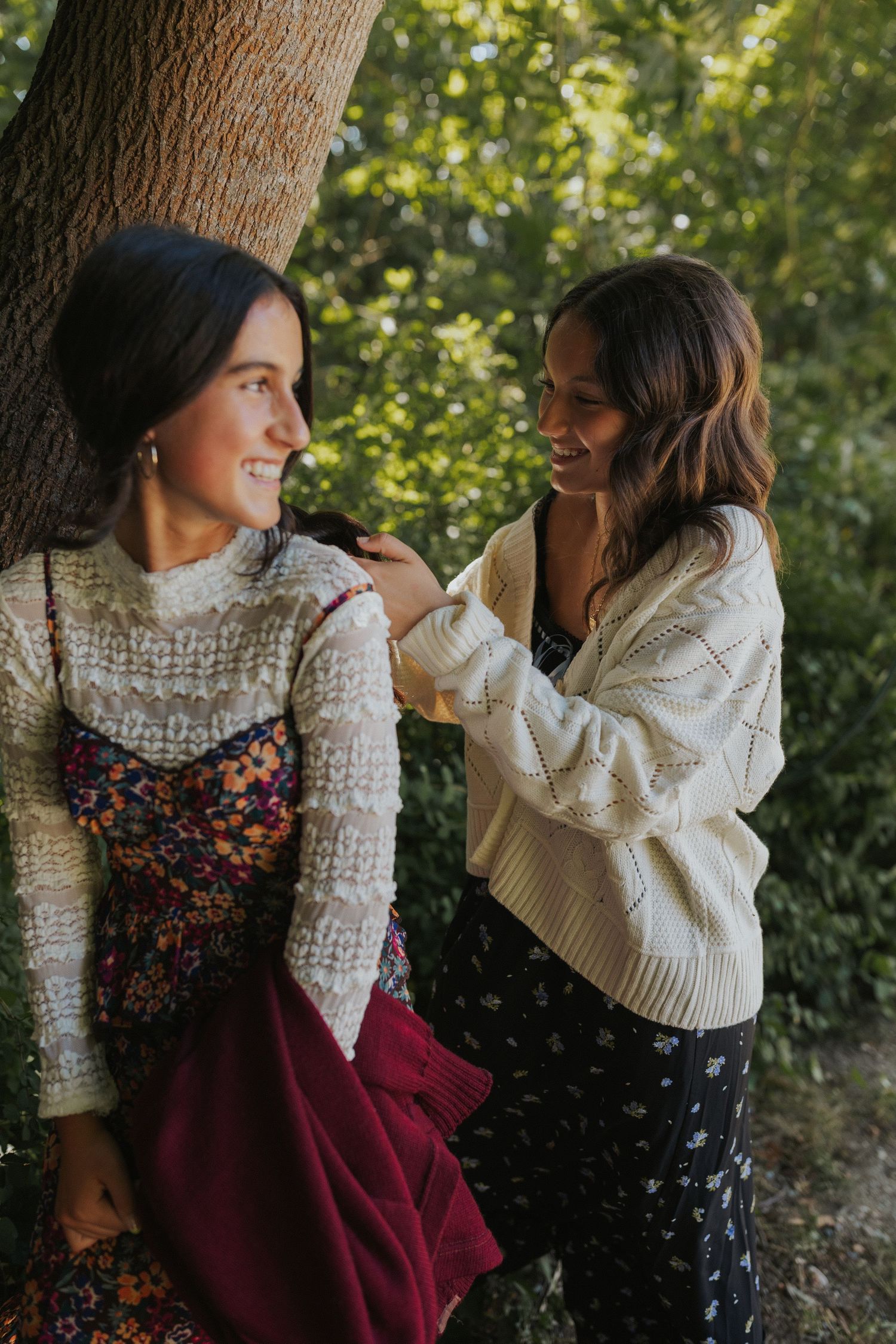 Two people in vintage-inspired outfits sharing a moment by a tree.