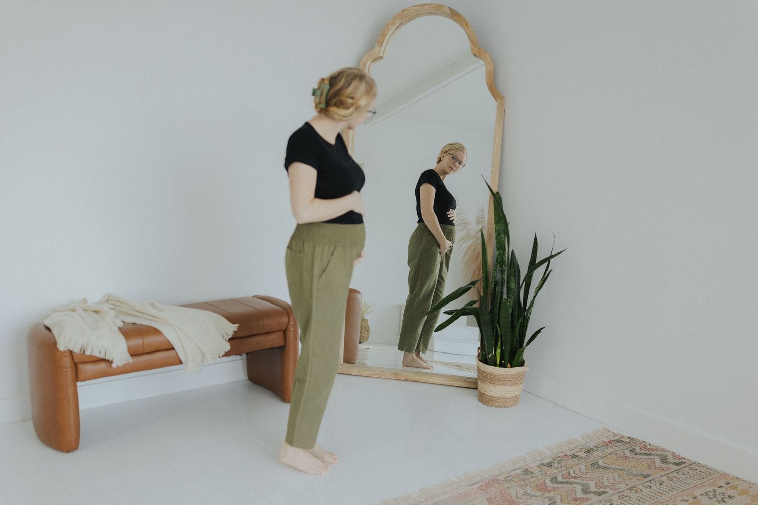 Minimalist white room interior with wooden mirror and potted plants.