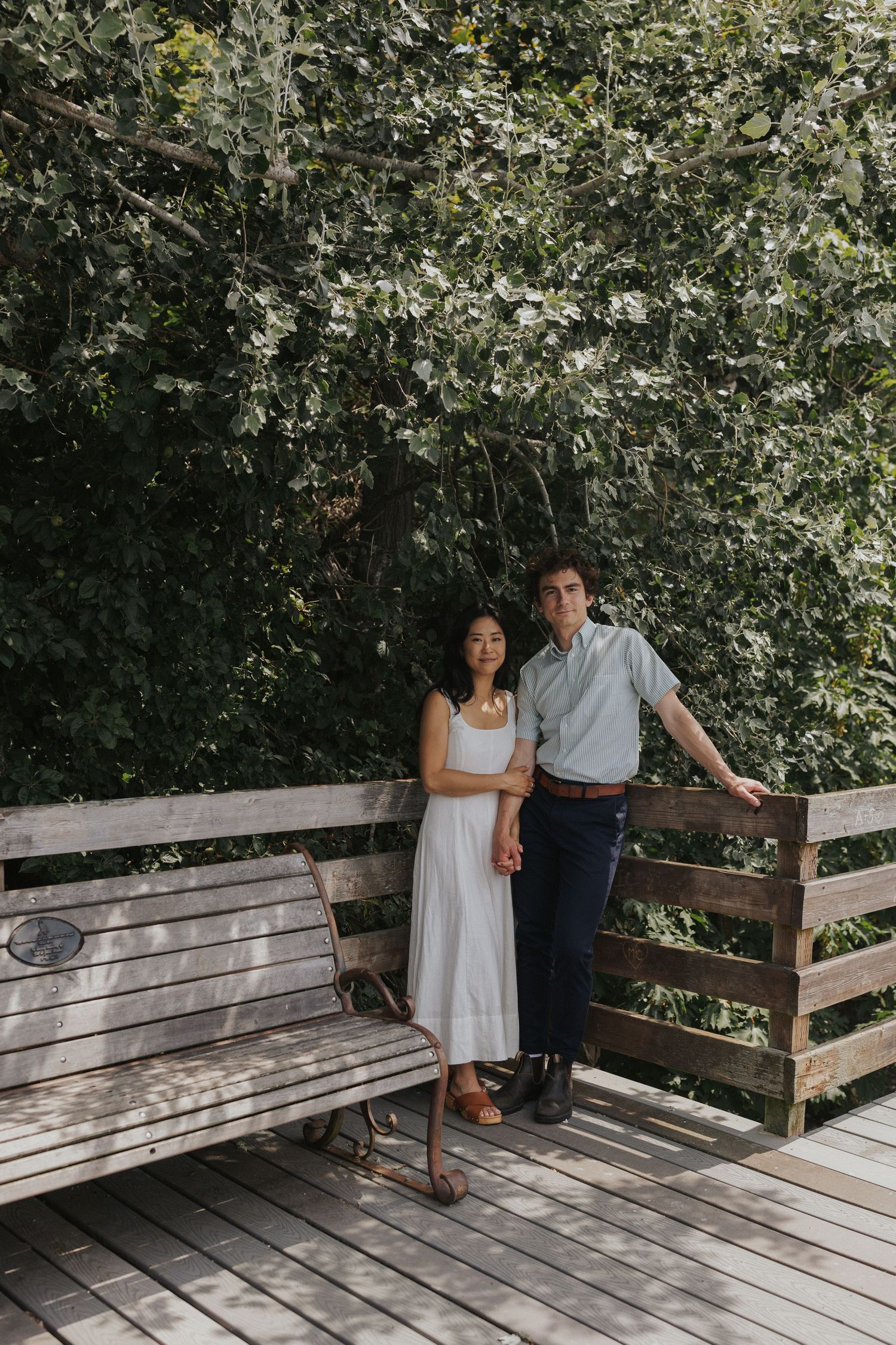 Couple sitting together on wooden deck surrounded by lush greenery.