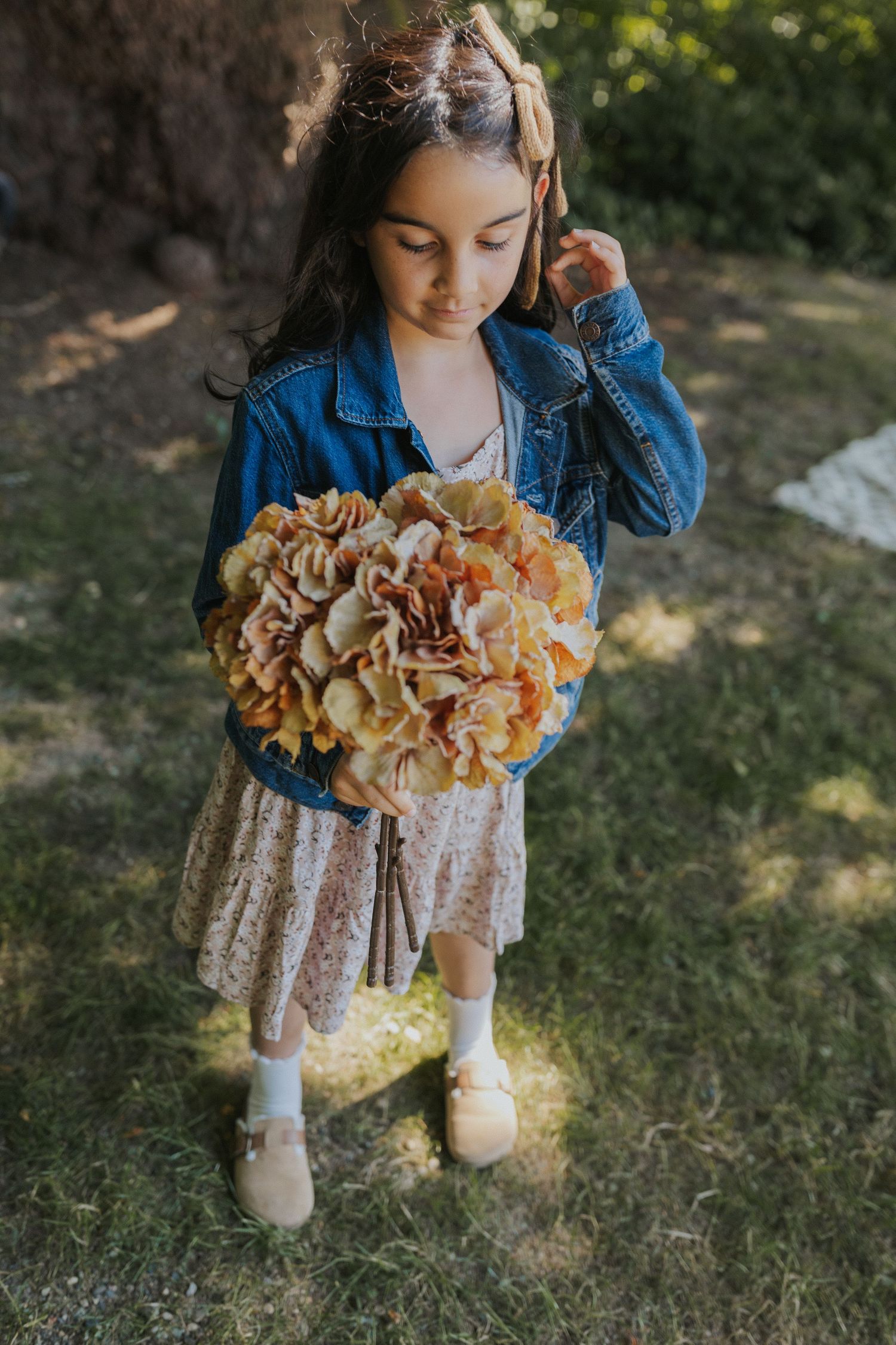 A bouquet of dried hydrangeas held against a white lace dress and denim jacket.