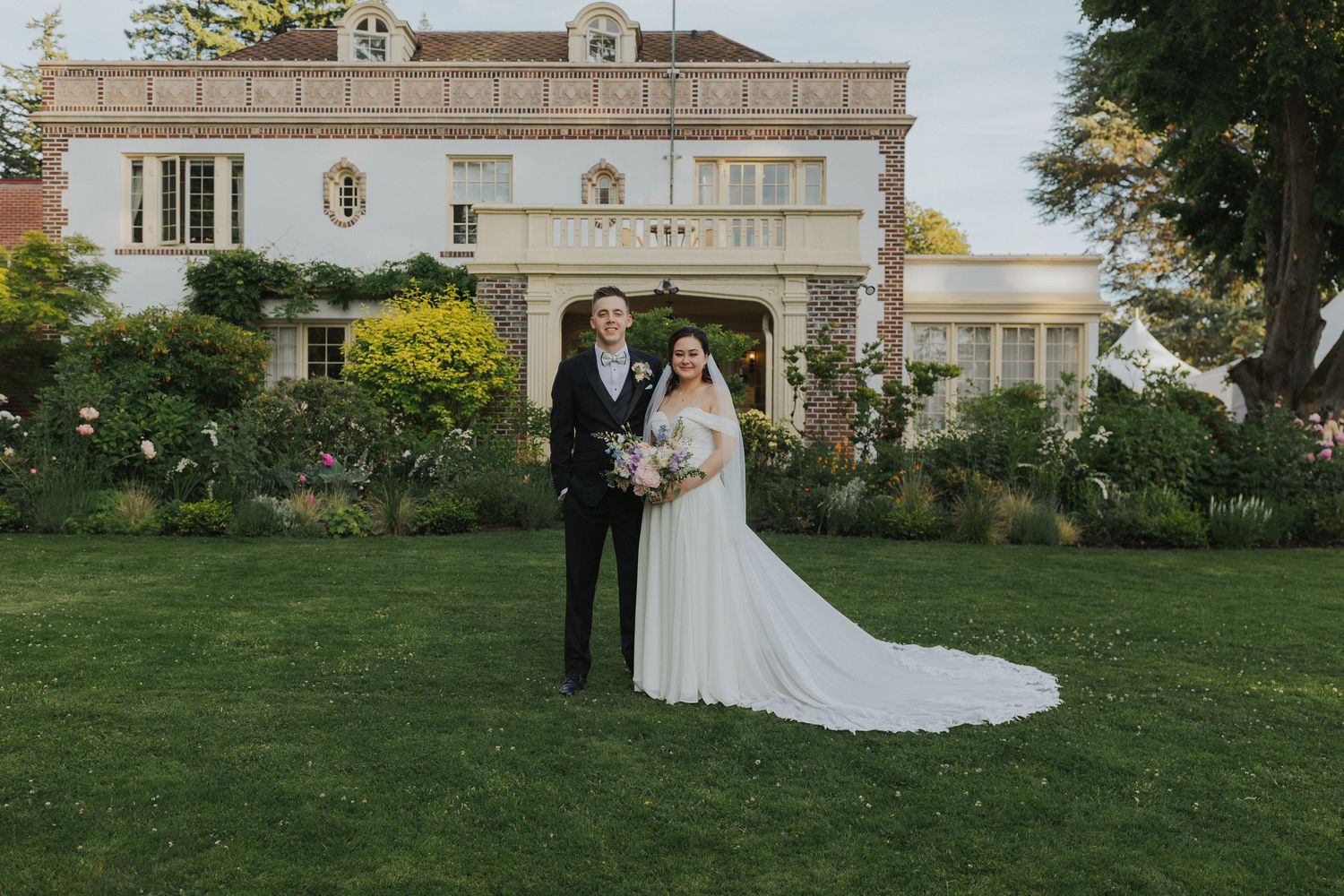 Wedding celebration on the grounds of an elegant white mansion with classical architecture.