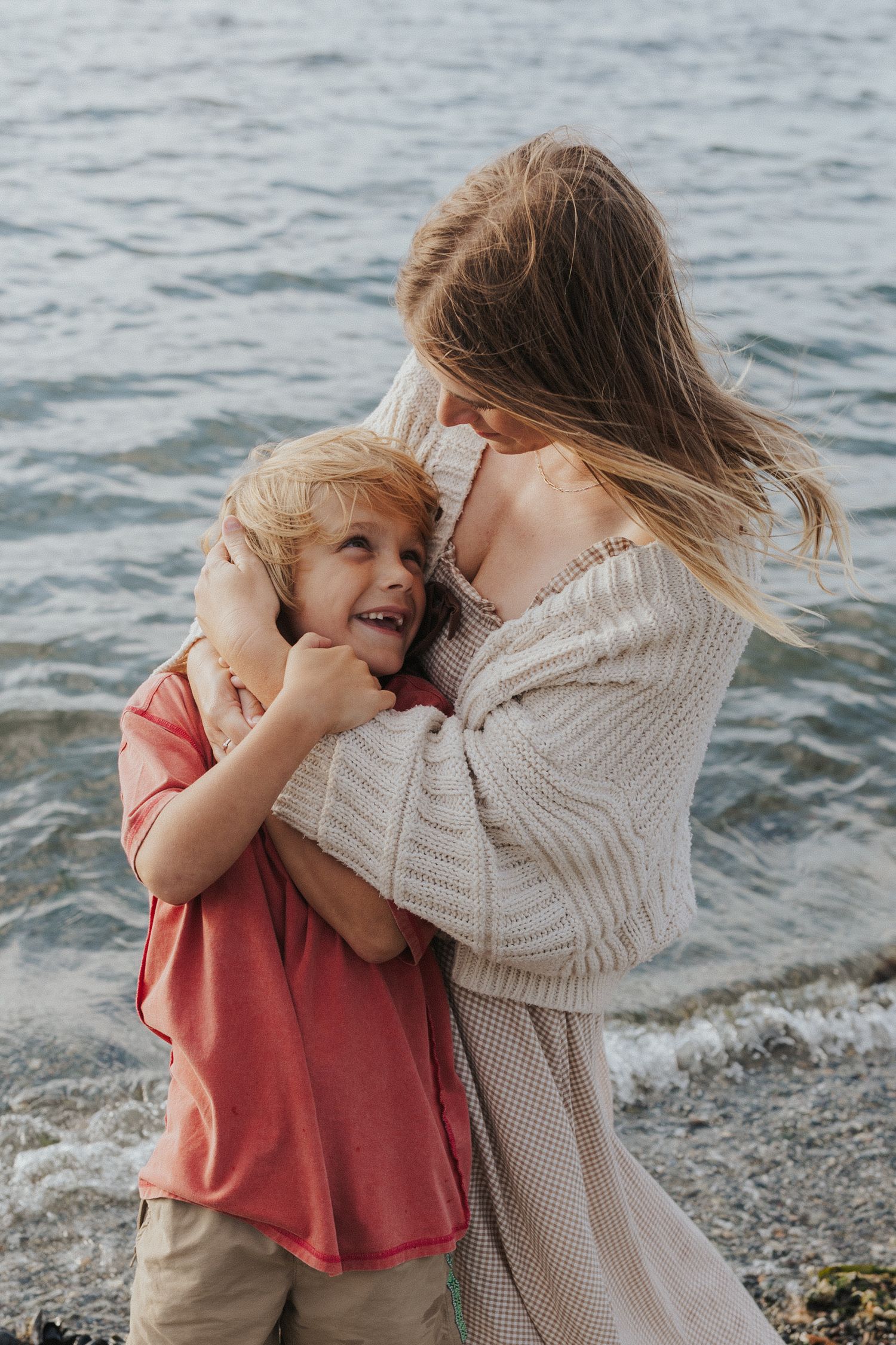 Sweet candid moment of affection and laughter on a rocky beach.