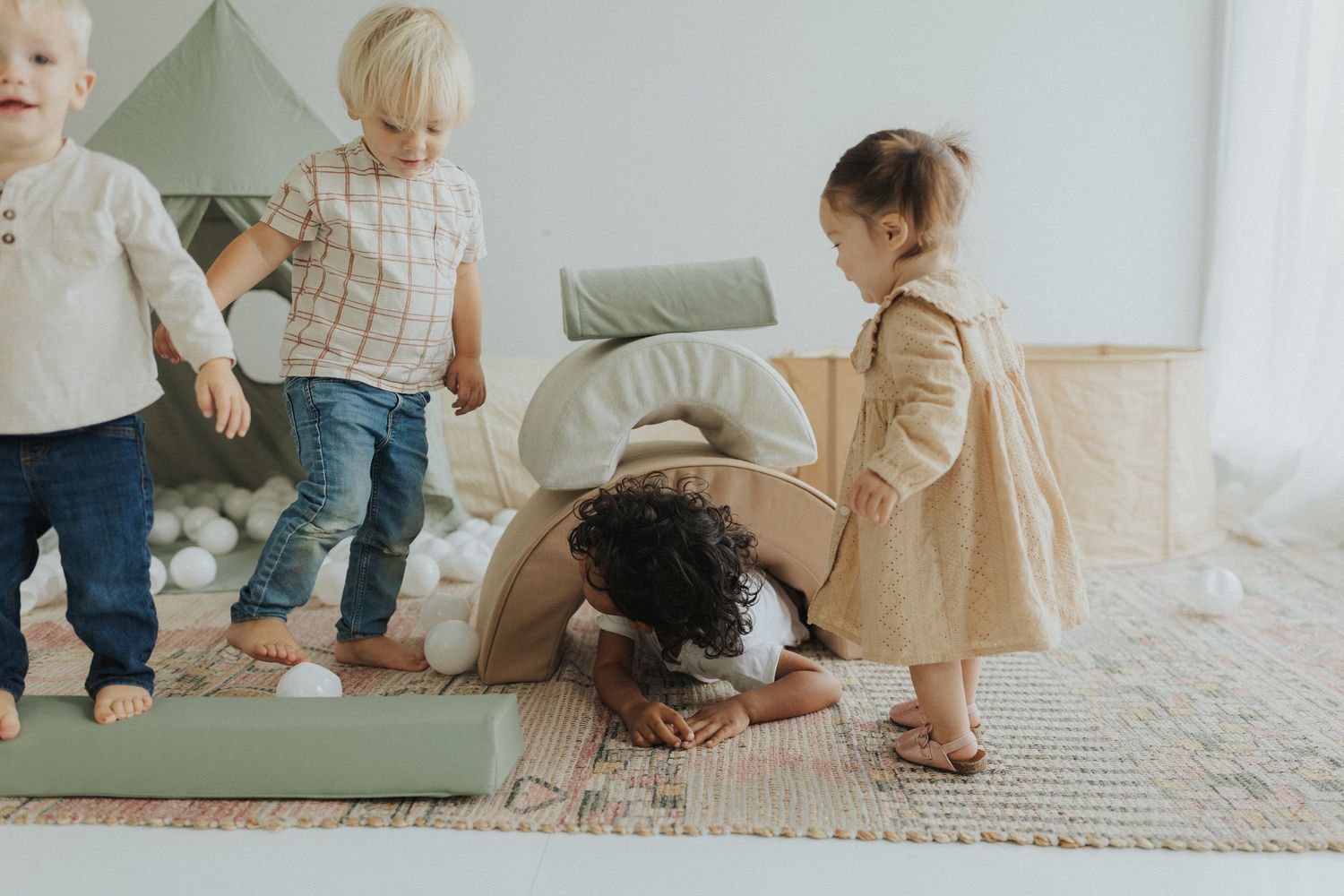 Three children play together on a cozy carpet in a bright living room setting.