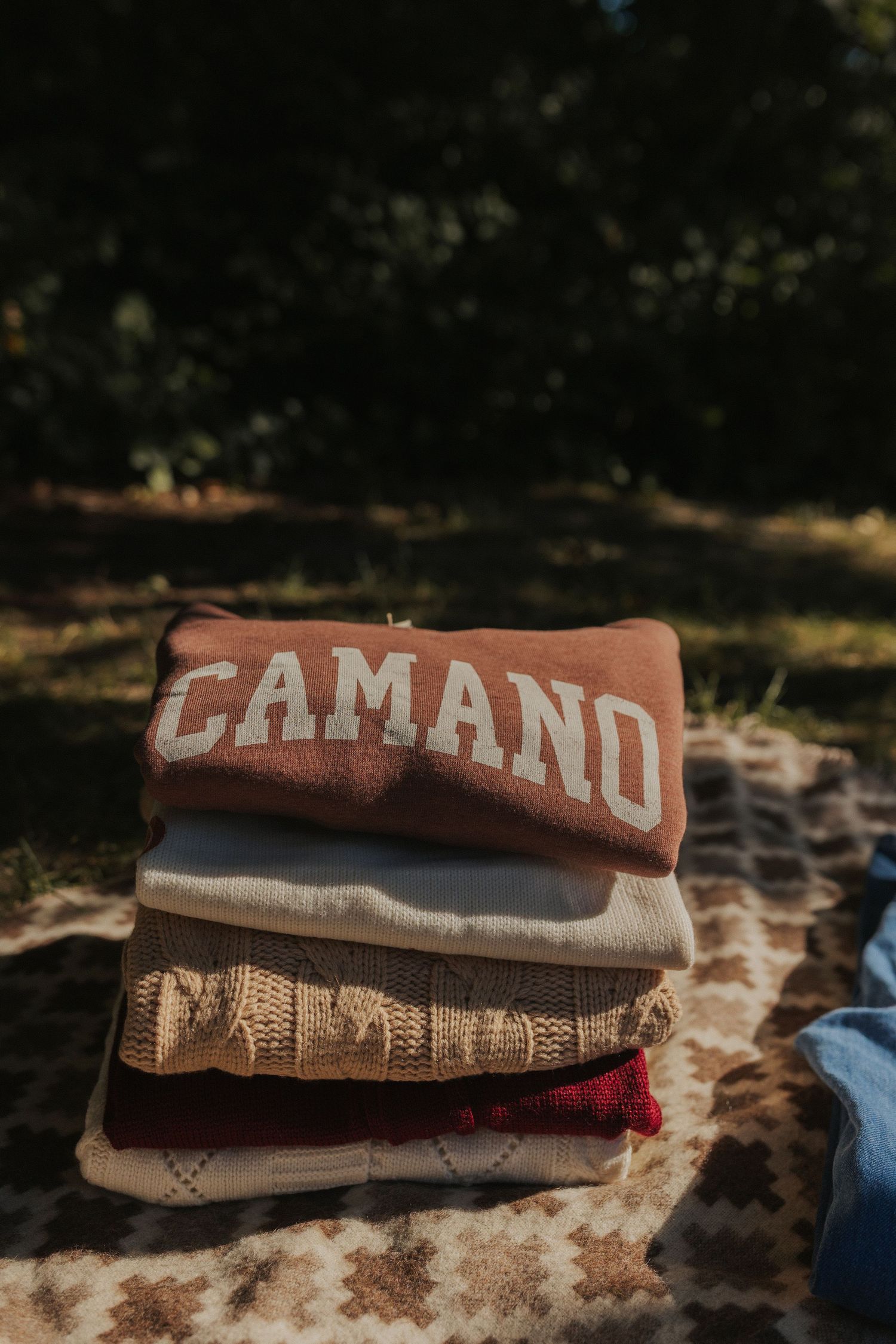 Neatly stacked clothing items with CAMANO text visible on a patterned surface.