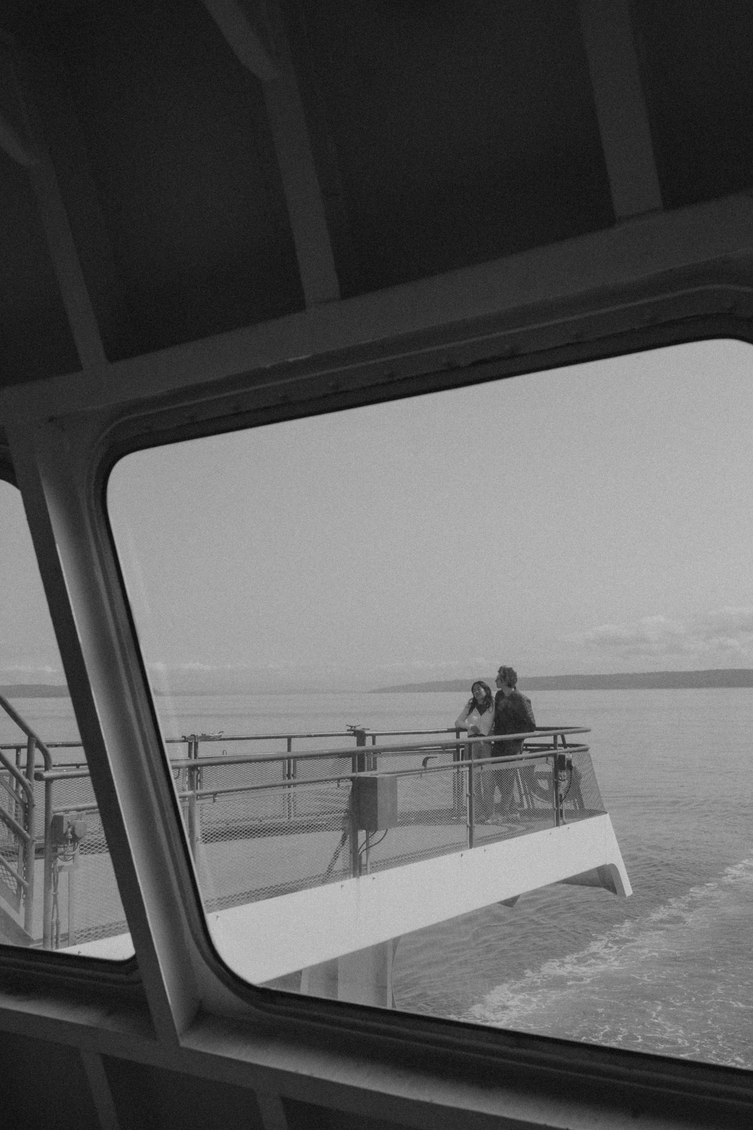 Black and white image of a ferry railing against a misty ocean horizon.