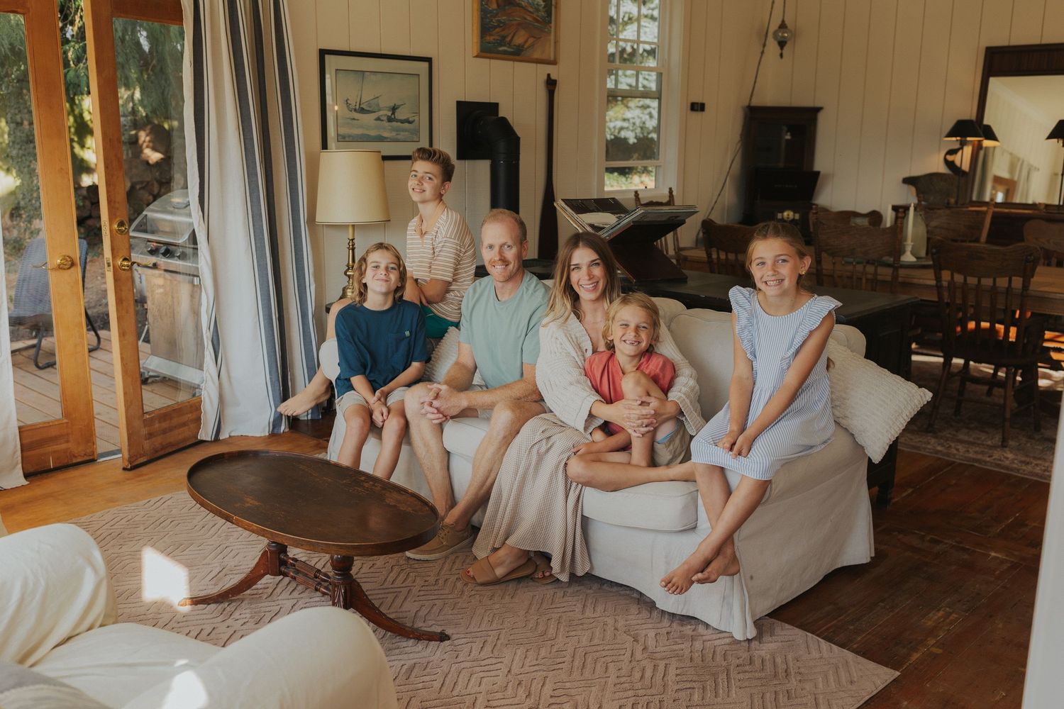 Family gathered together in bright living room with white furniture and natural light.