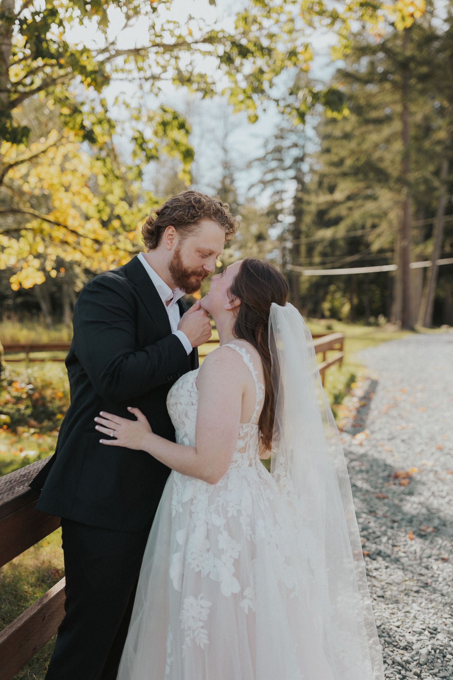 Intimate wedding moments captured along a gravel path with golden autumn leaves in the background.