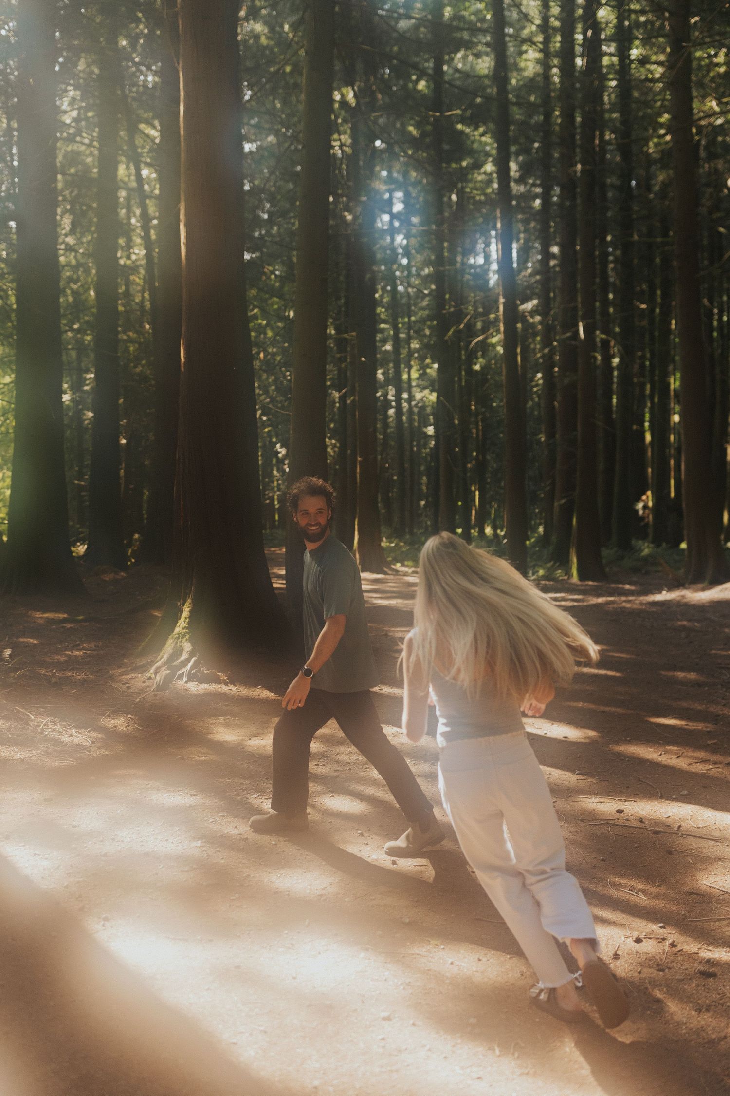 Dreamy sunlight creates a magical atmosphere as a couple dances in a peaceful forest.