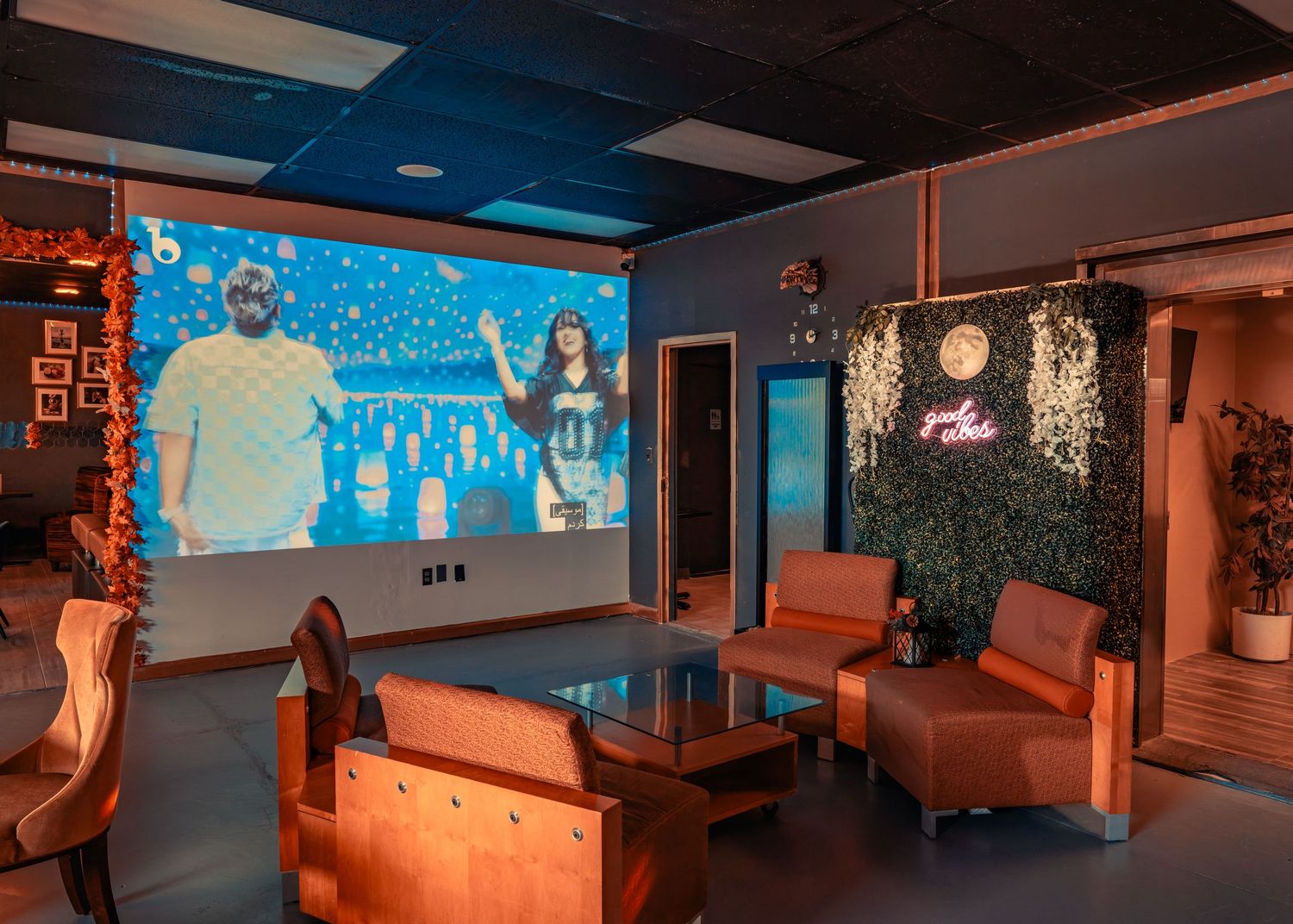 Modern Hookah Lounge interior with orange lighting and multiple screens mounted on walls showing workout content.