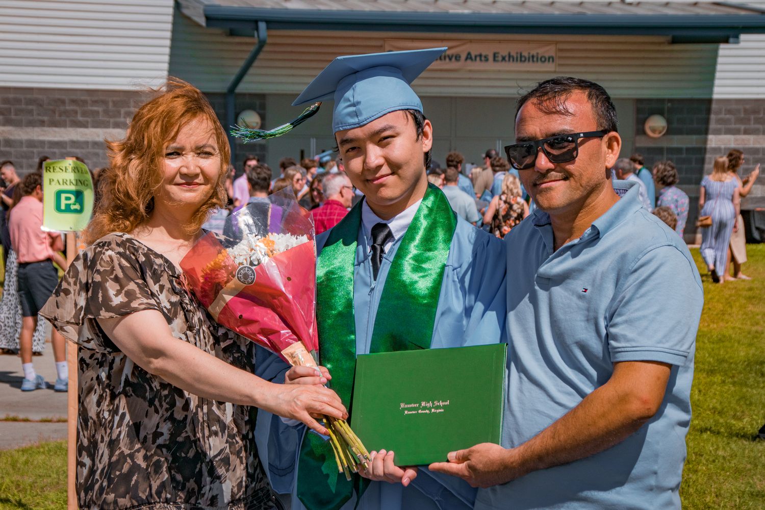 Family poses with graduate during outdoor graduation celebration.
