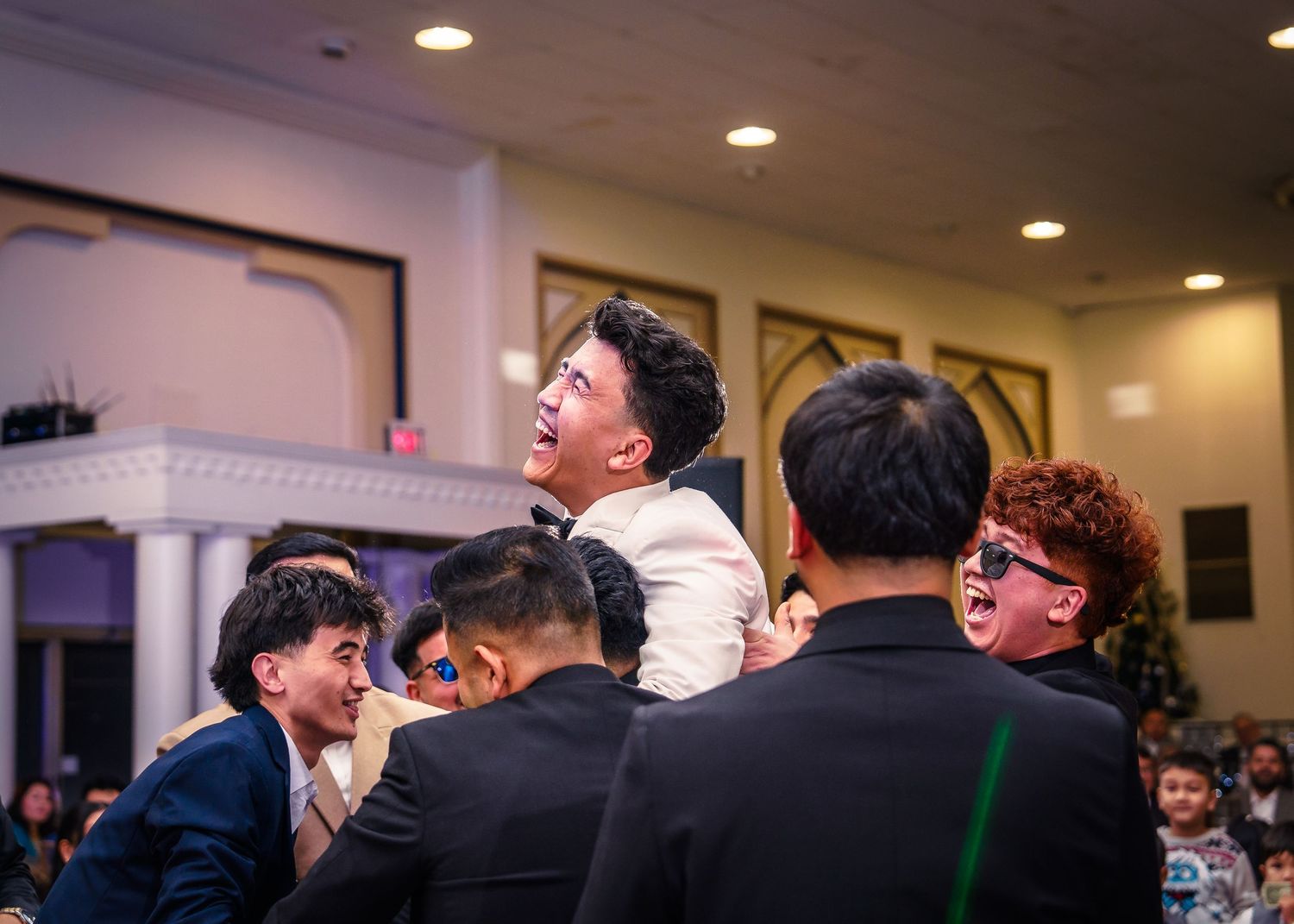 A panoramic view of people laughing and enjoying themselves at an indoor social gathering.