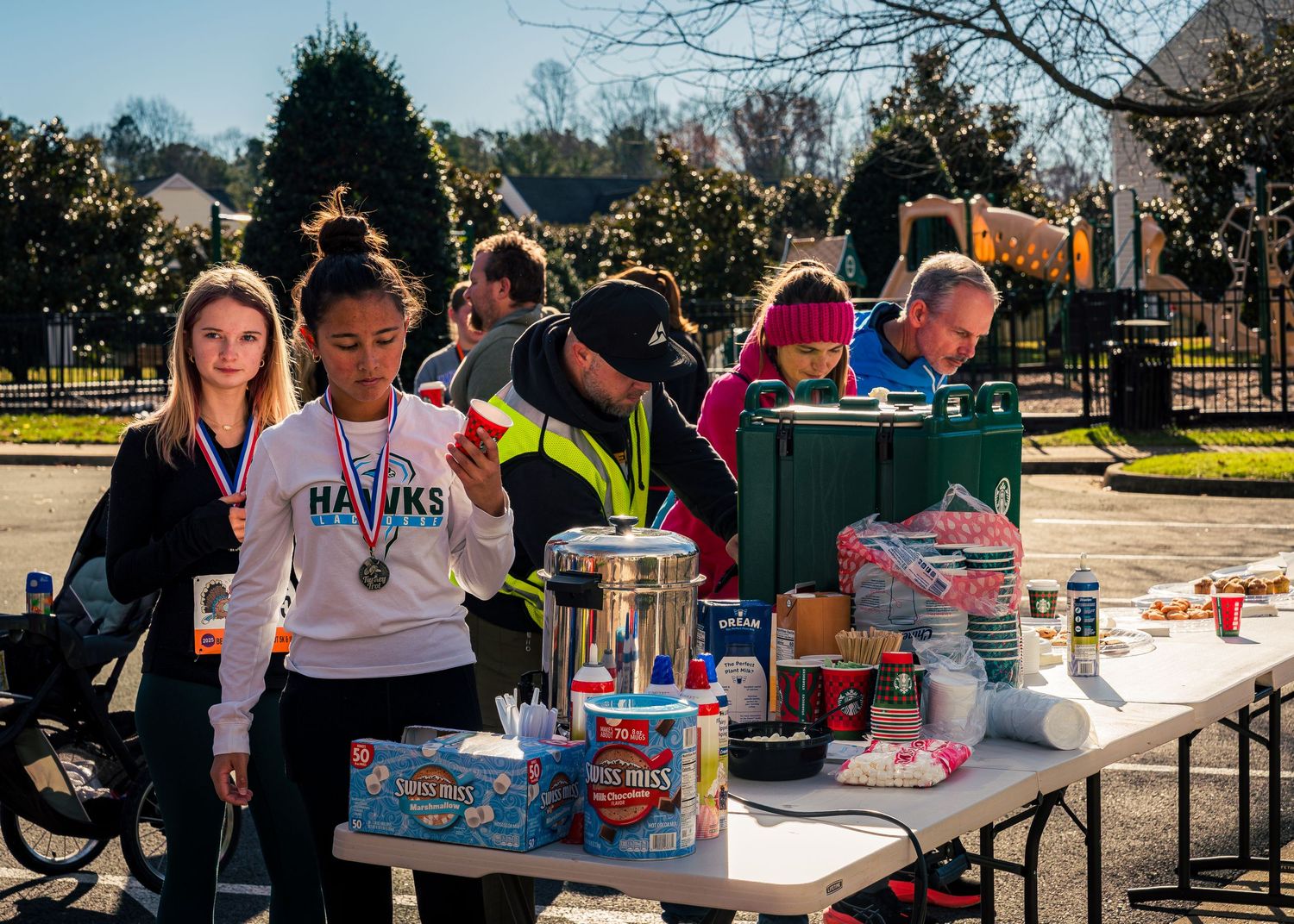 People gathered at outdoor tables participating in a community craft or activity event on a sunny day.