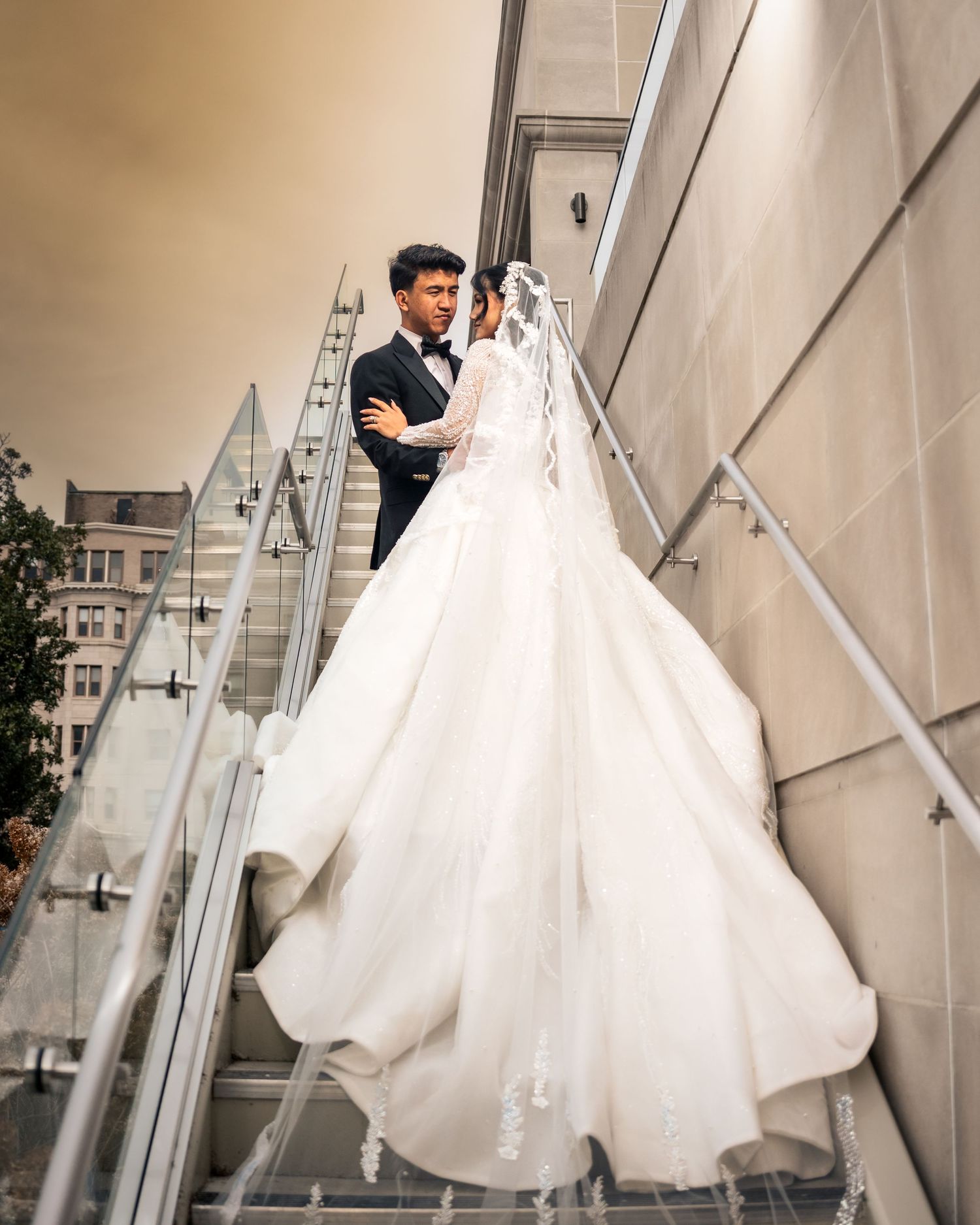 A sequence of elegant white wedding gowns displayed on hangers against a light-colored wall.