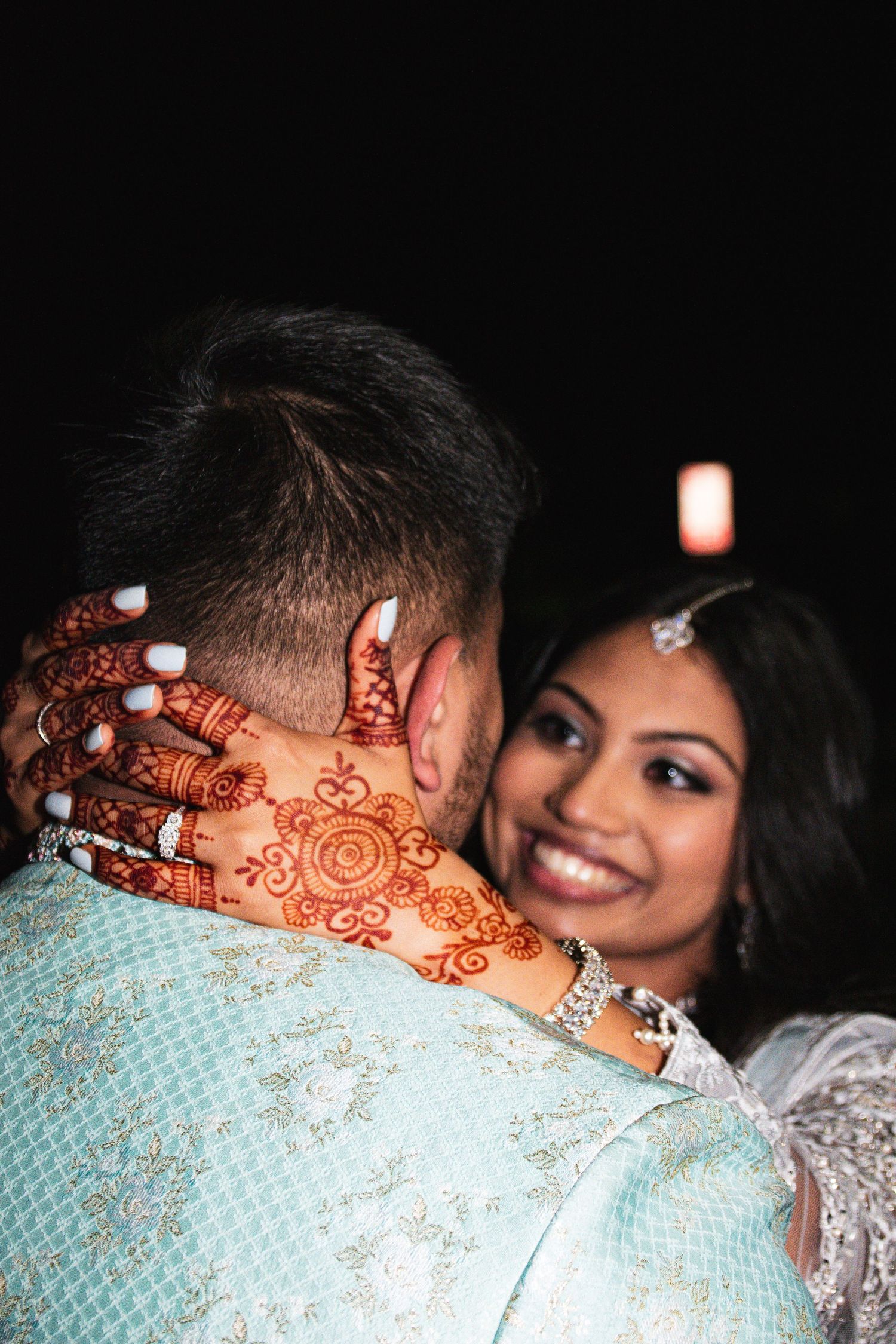 Beautiful mehndi design displayed on hands during a South Asian wedding celebration.