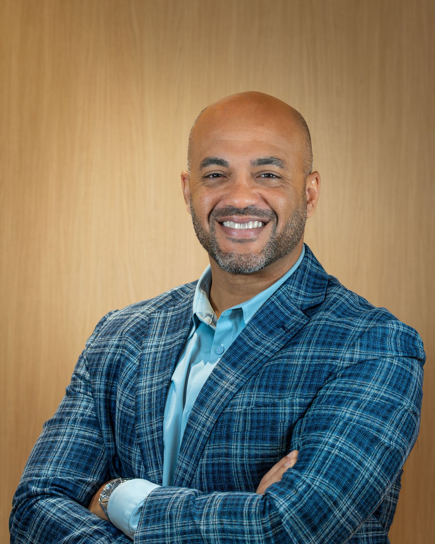 Professional headshot series showing expressions in a blue plaid blazer and white shirt against a warm background.