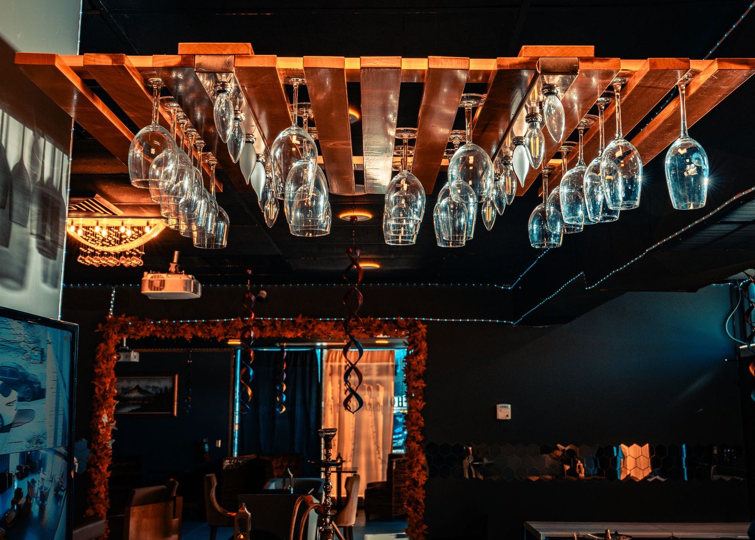 A dark moody bar interior with hanging glass light fixtures and orange ambient lighting creating an intimate atmosphere.