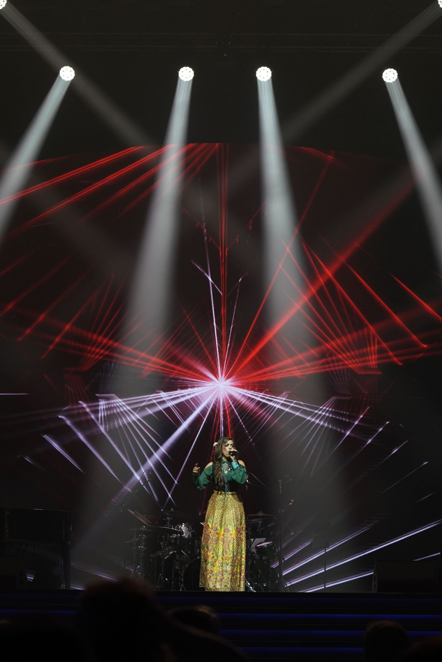 Stage performance with dramatic white spotlights and red laser light effects.