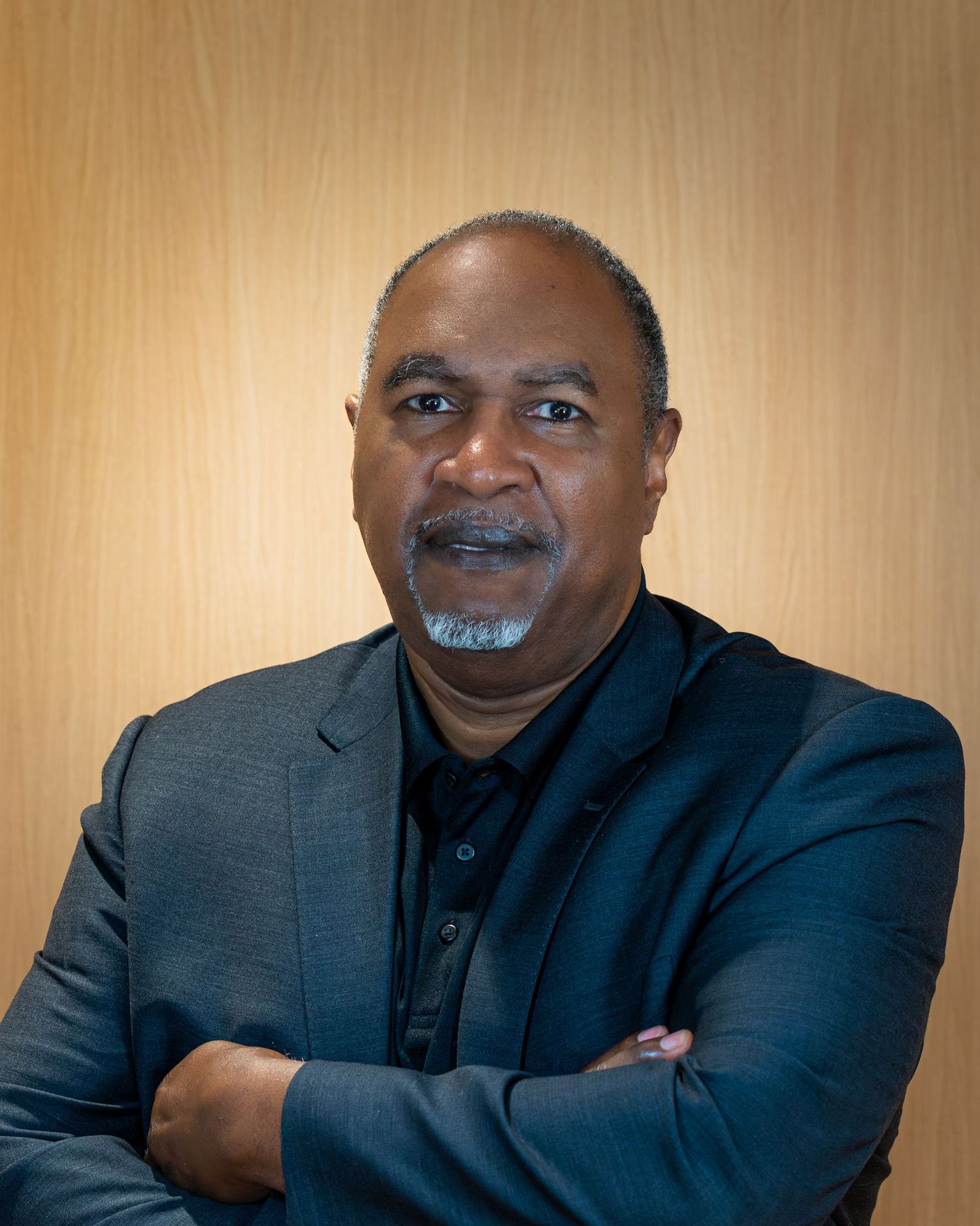 A series of four professional headshots showing a person in a dark suit against a beige background.