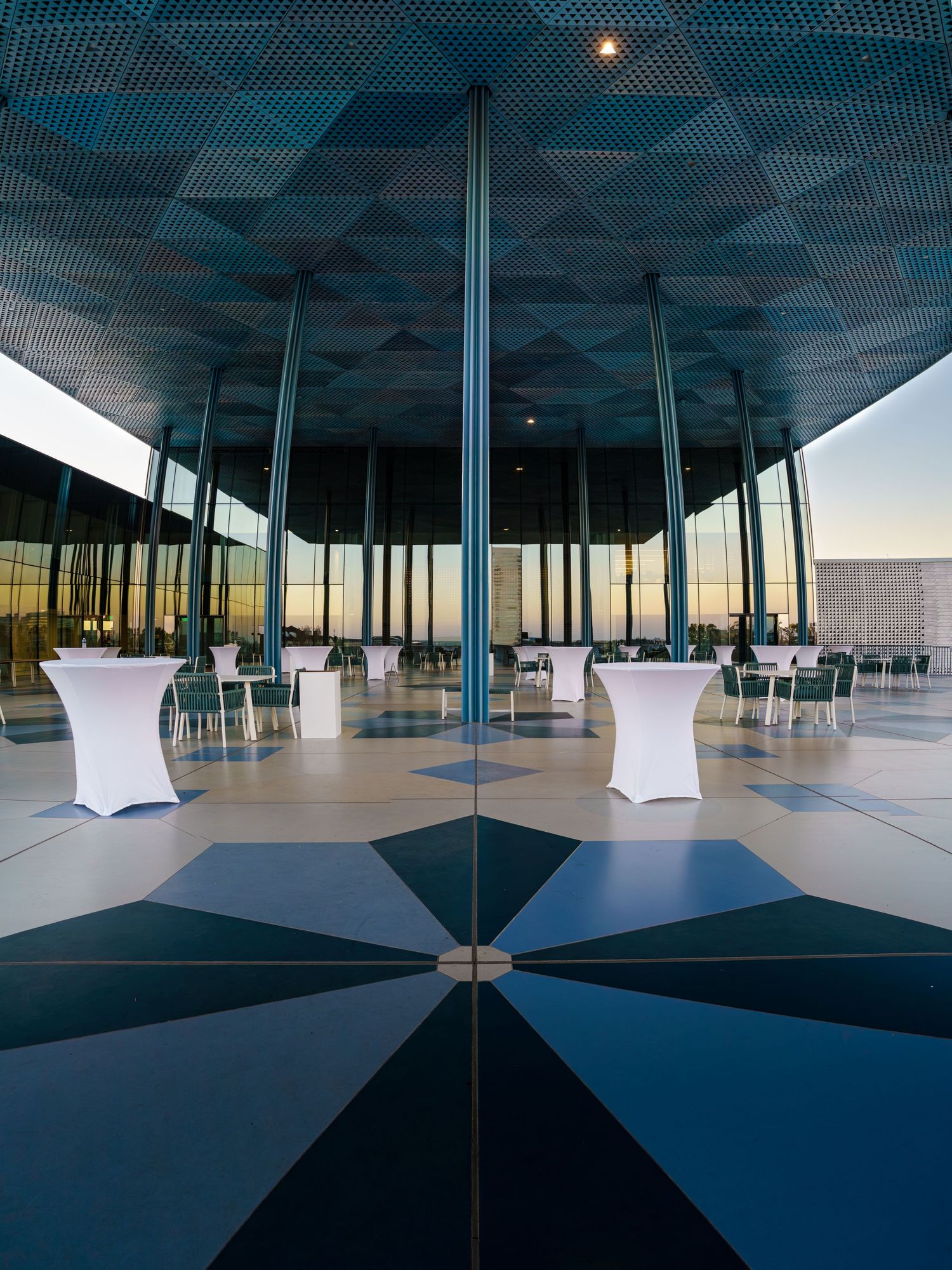 Modern architectural interior with geometric ceiling patterns and glass walls creating a sleek contemporary space.