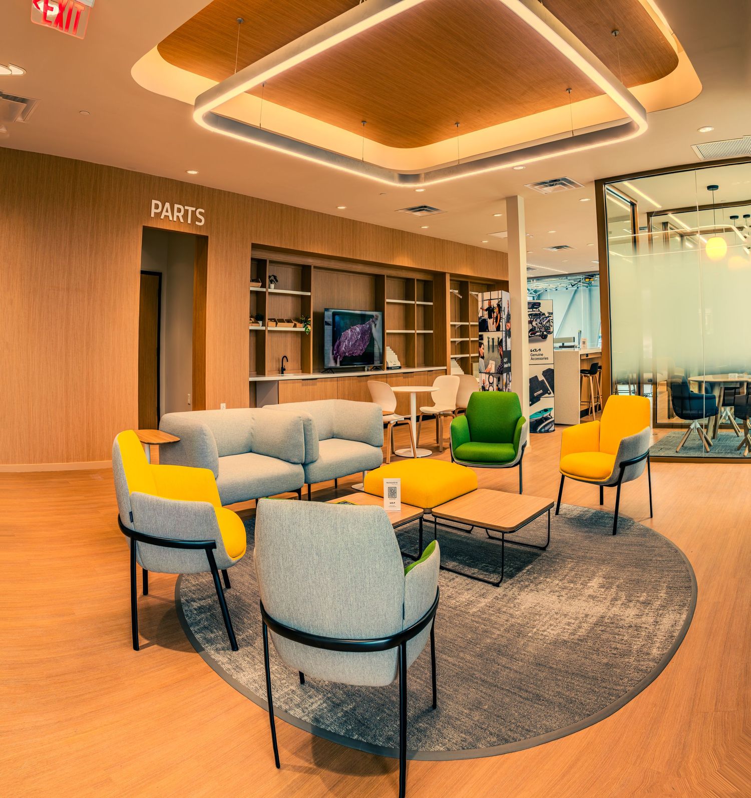 Modern office lounge area with colorful seating arrangements and warm lighting under recessed ceilings.