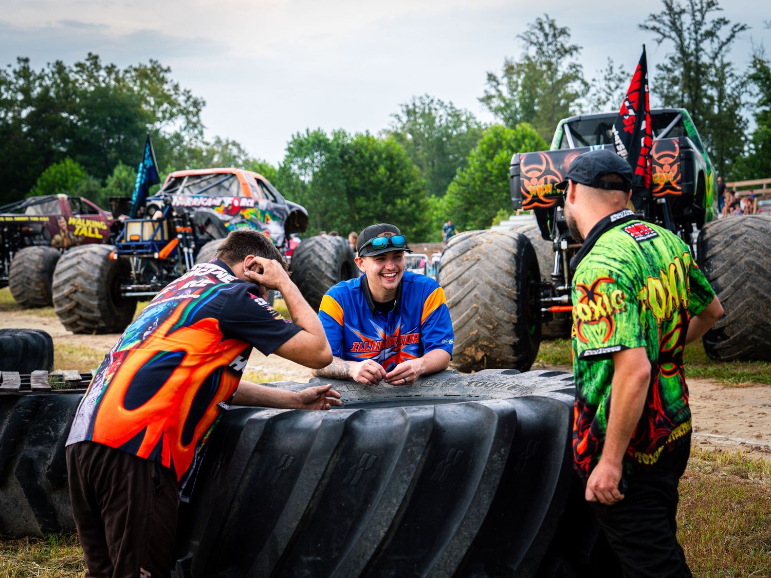 A group of people compete in a challenging obstacle course by climbing over large tractor tires in an outdoor event.