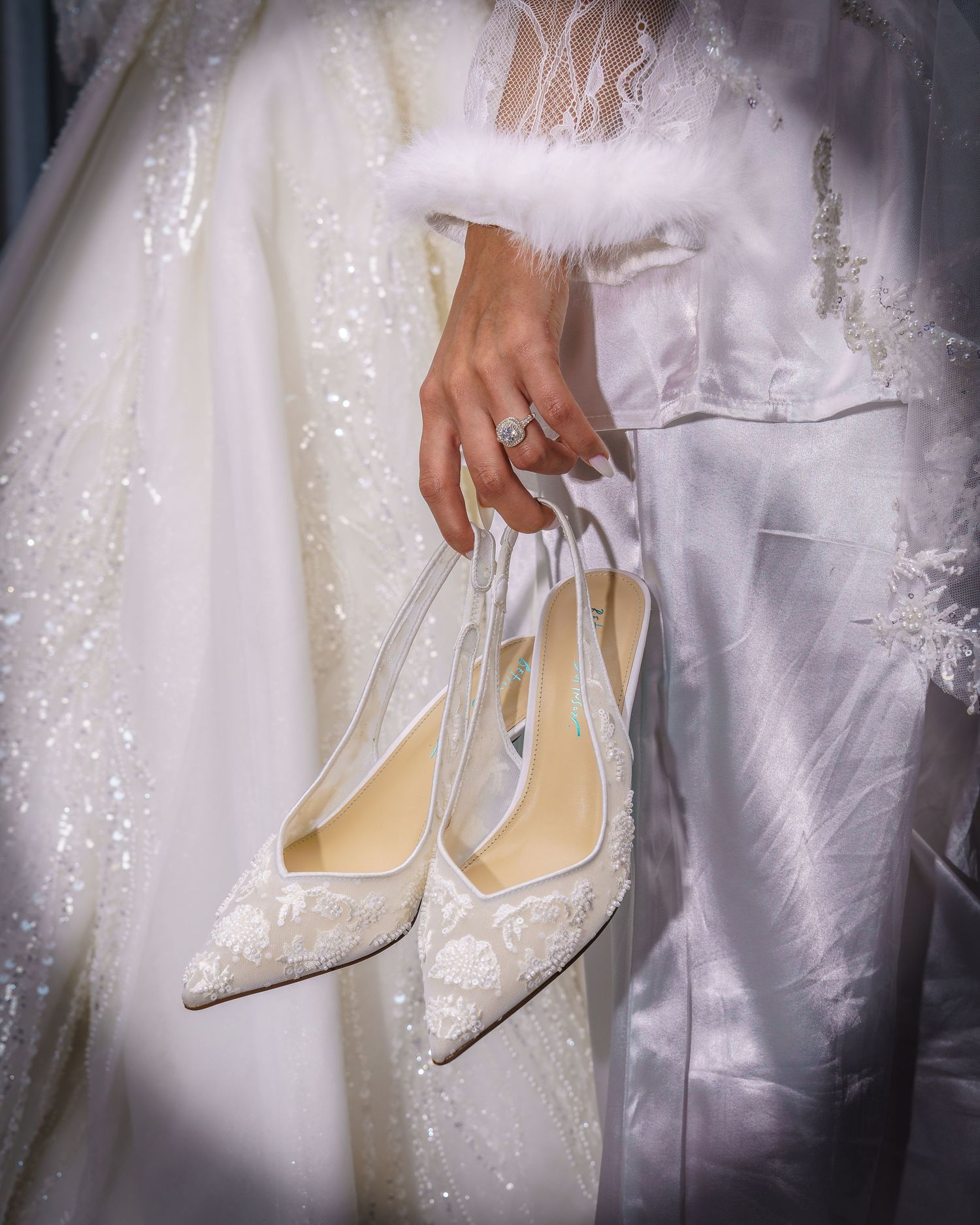 Elegant white bridal heels with sparkly embellishments displayed in a soft, ethereal lighting setup.