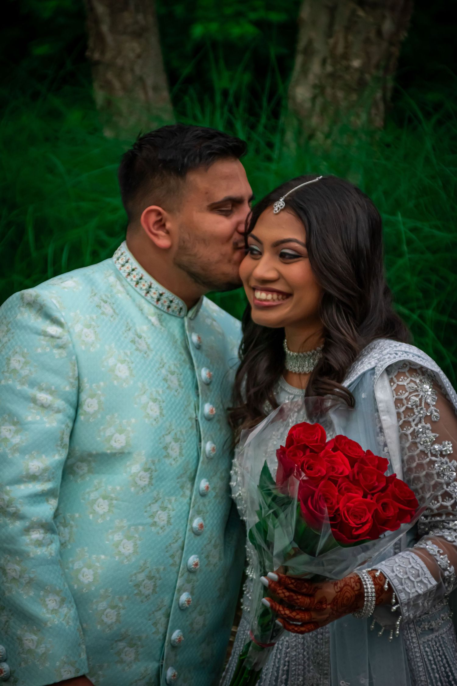 Sweet engagement photos featuring mint sherwani and white lace dress with vibrant red roses.