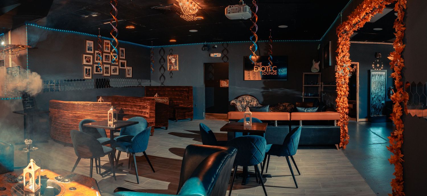 Dimly lit Hookah Lounge interior with exposed brick walls and moody blue lighting creating an atmospheric ambiance.