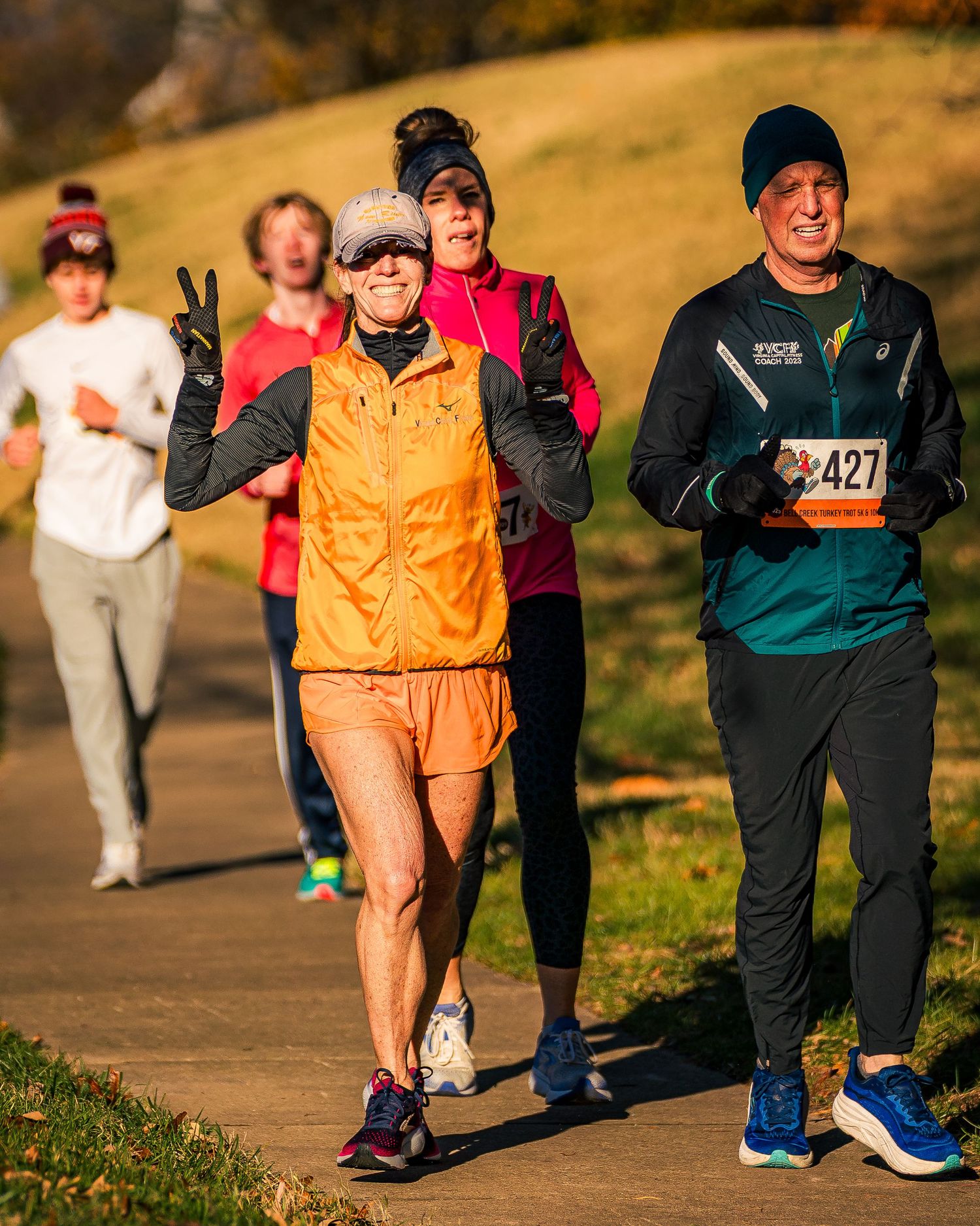 Runners enjoying a sunny autumn day on a paved path during a race event.