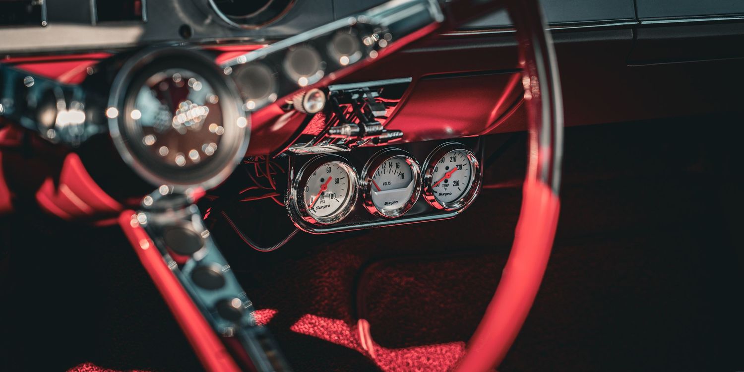 Close-up view of red illuminated car dashboard gauges and instrument panel at night.