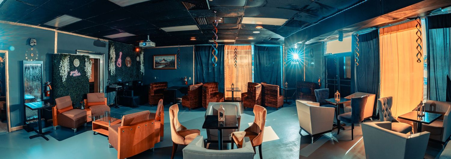 Modern lounge interior with teal walls, brown leather seating and ambient blue lighting creating a relaxing atmosphere.