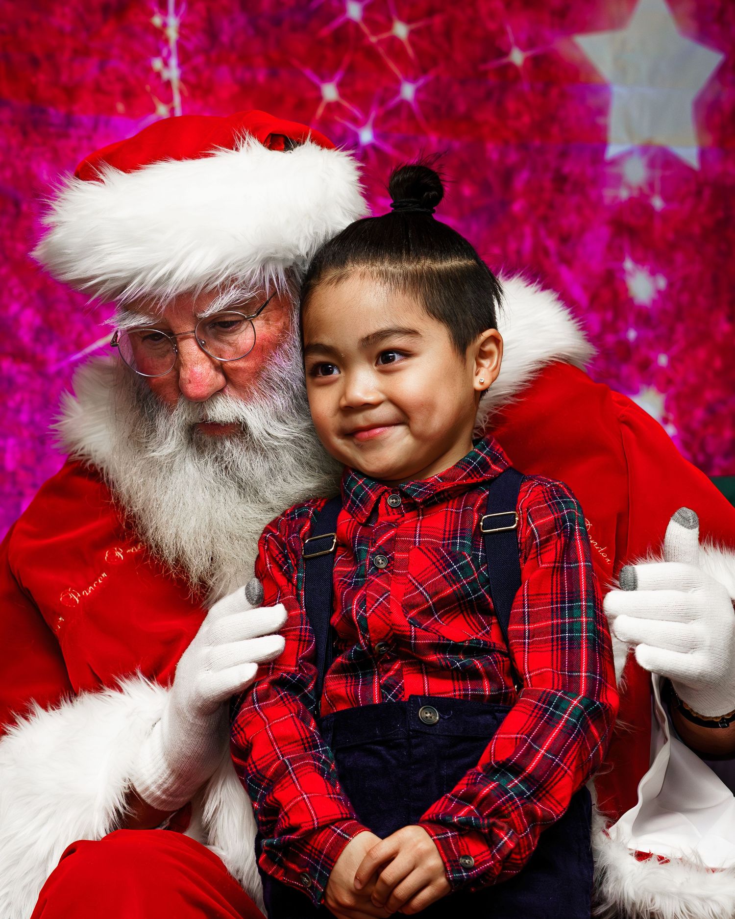 A festive holiday portrait against a bright pink background with sparkly star decorations.