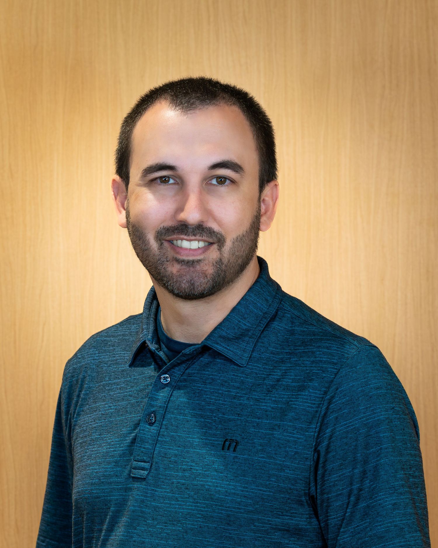 Progressive headshots displaying different angles in a dark blue textured polo against a tan backdrop.