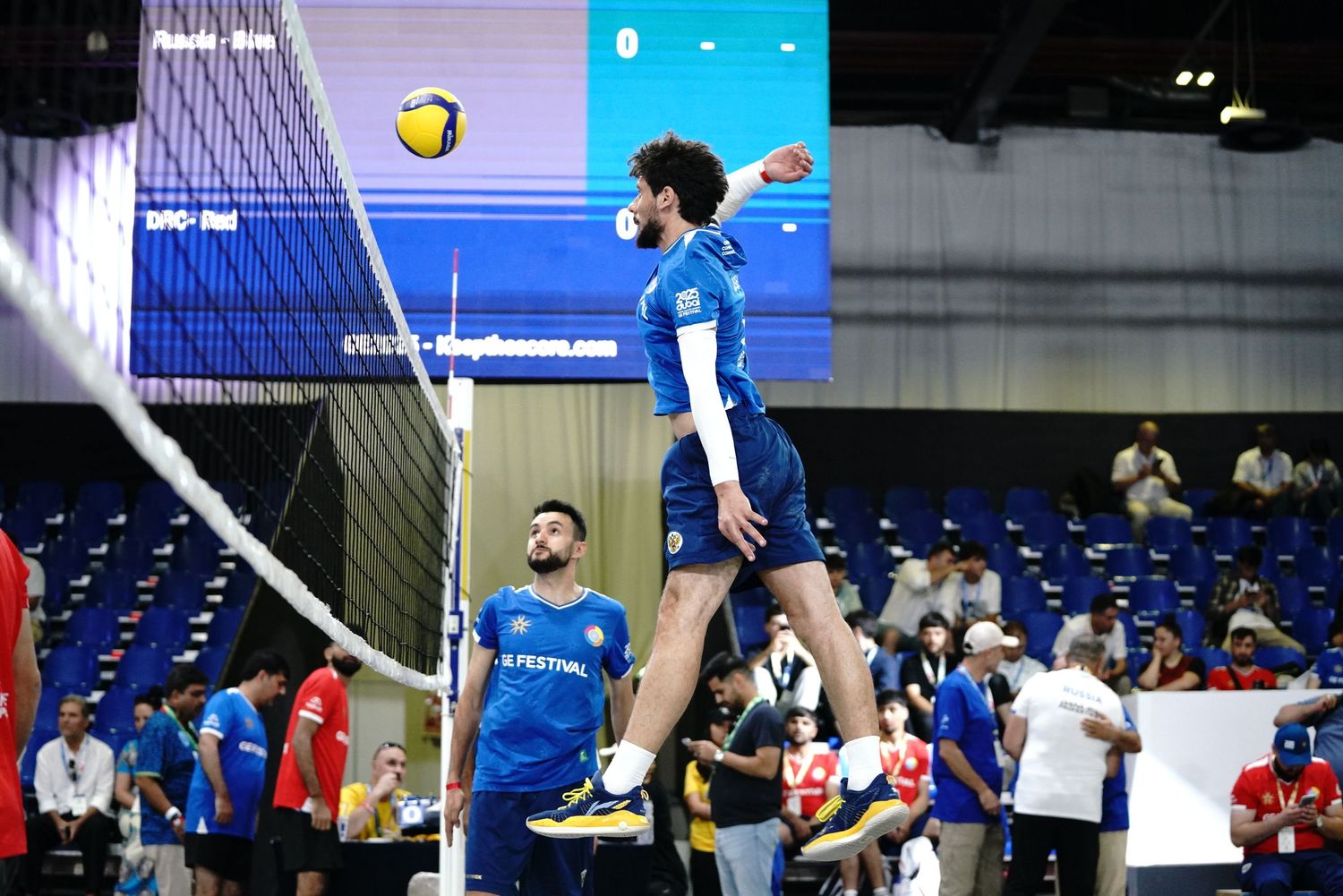 Volleyball players preparing to serve during a competitive indoor match.