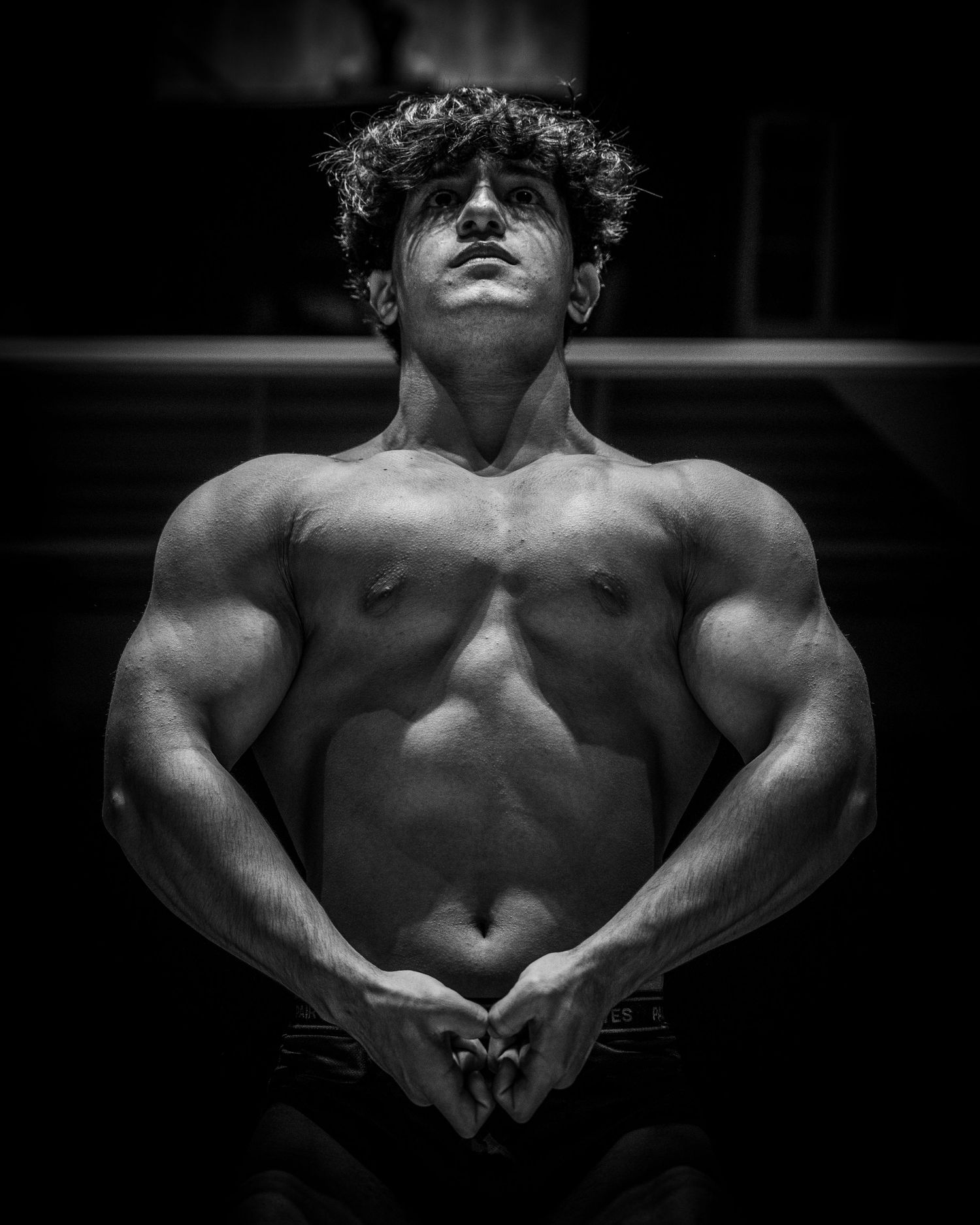 Dramatic black and white artistic photo series showing muscular male torso with shadows highlighting physique details.