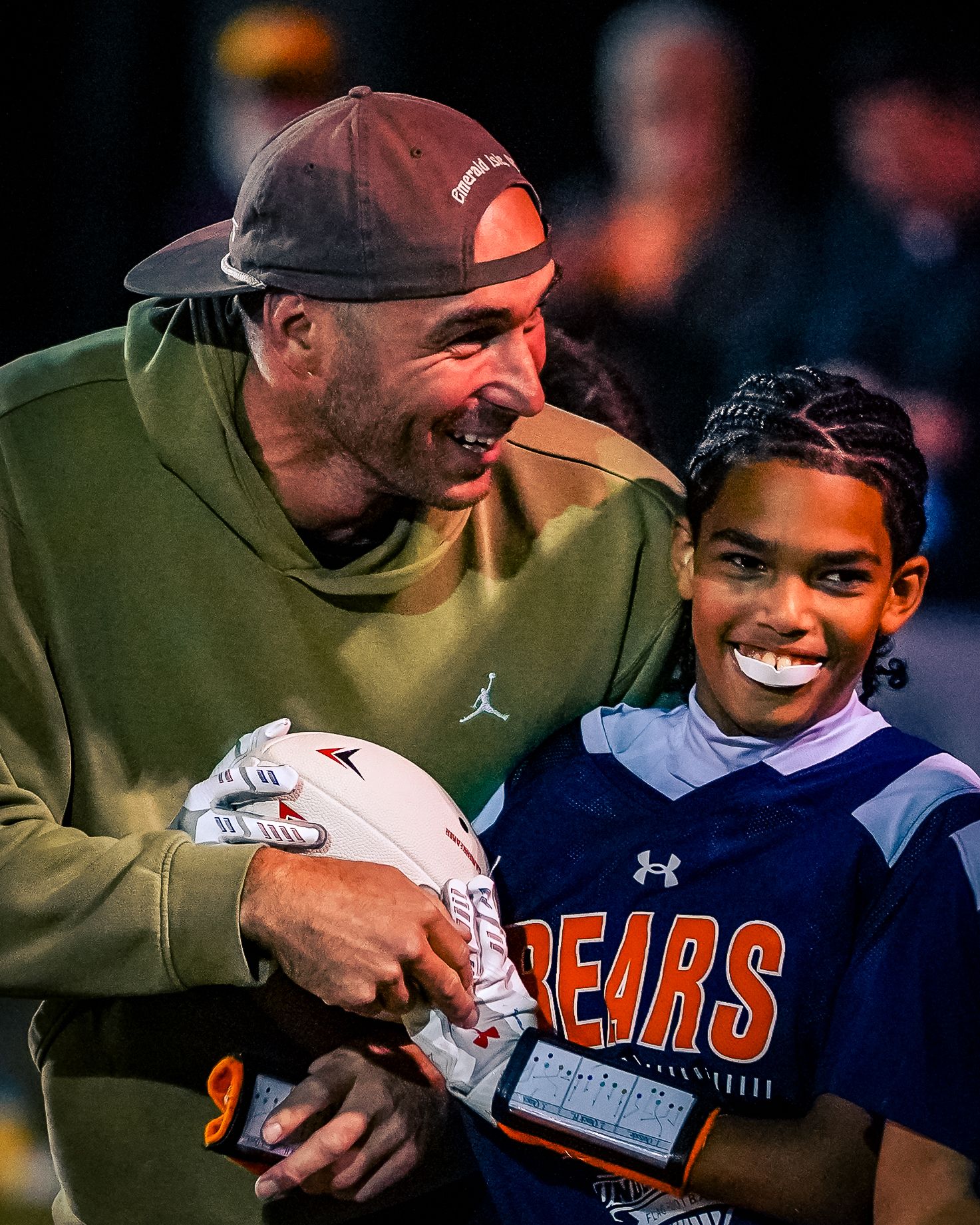 Two people share a joyful moment while wearing sports apparel with Bears team branding.