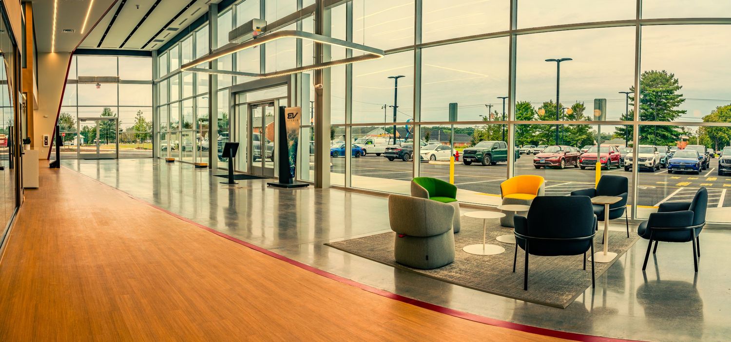 Wide panoramic view of a modern office interior with glass walls, sleek furniture and natural lighting.